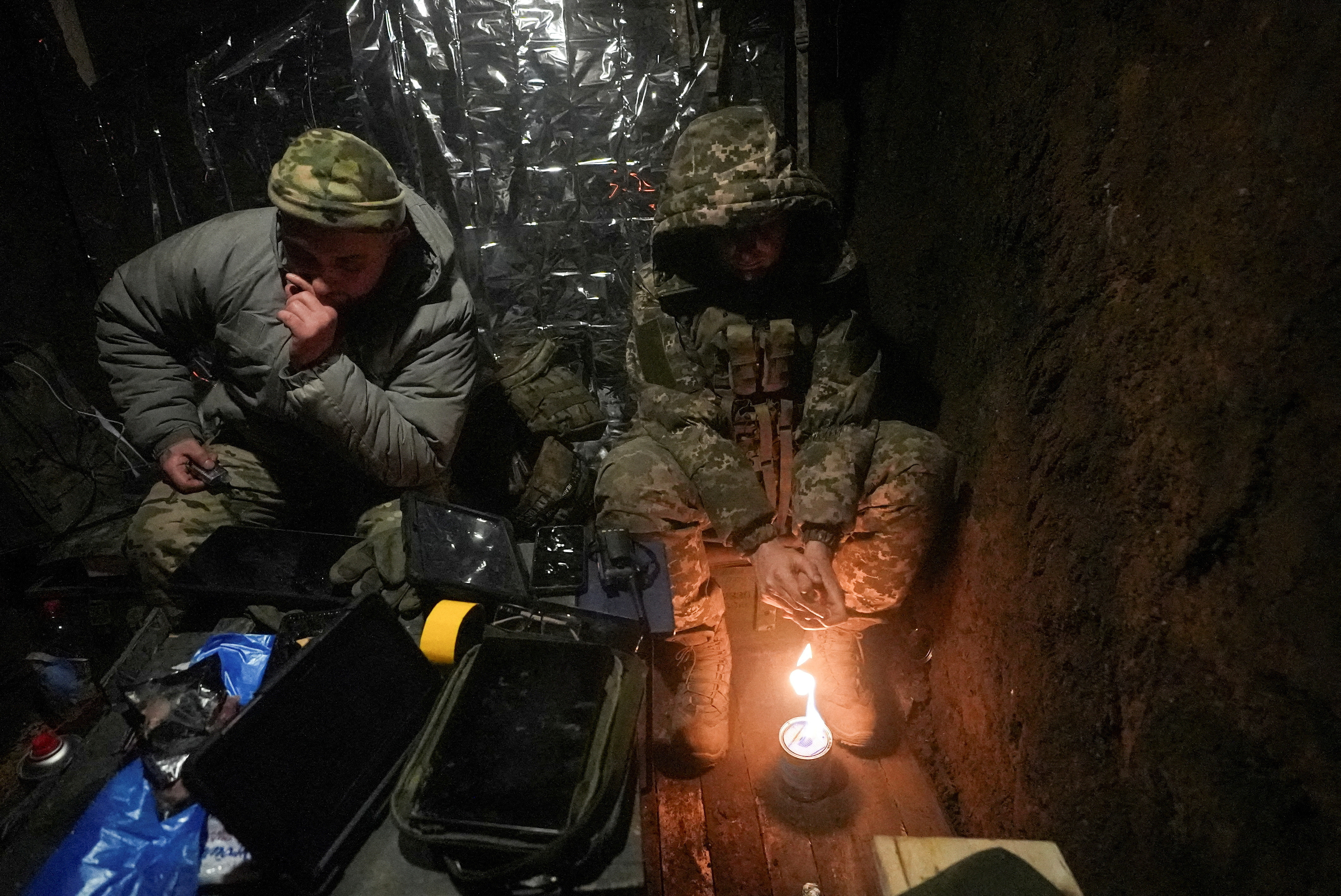 Ukrainian servicemen warm up inside a dugout as they fly with a Vampire combat drone over positions of Russian troops near the frontline town of Bakhmut