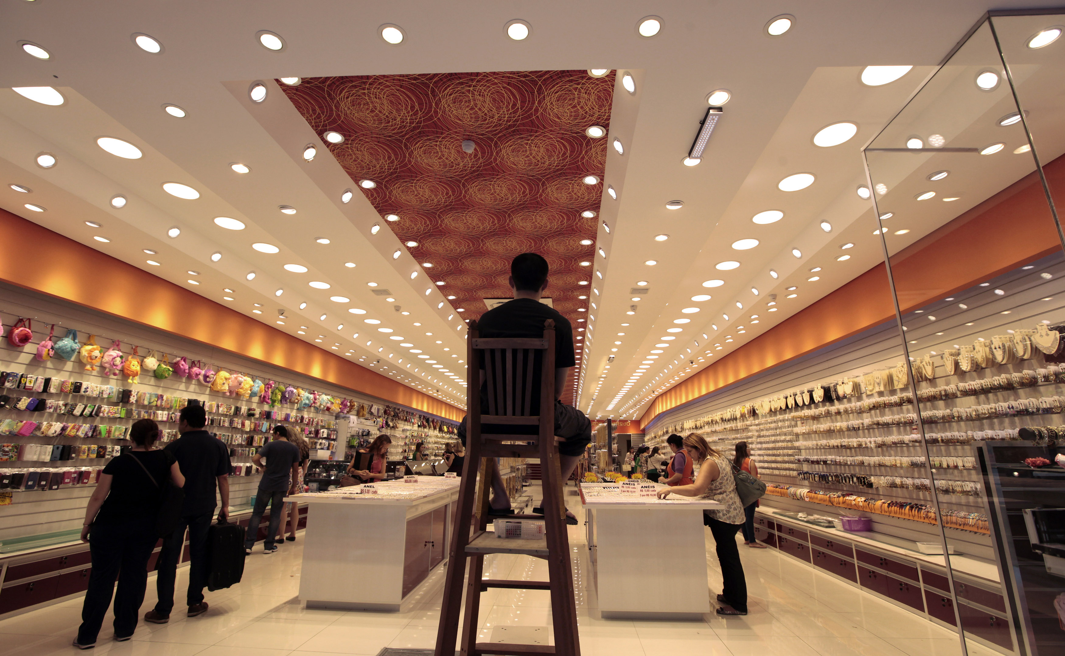 A security guard stands guard on the top of a chair as consumers shop in a store in downton Sao Paulo