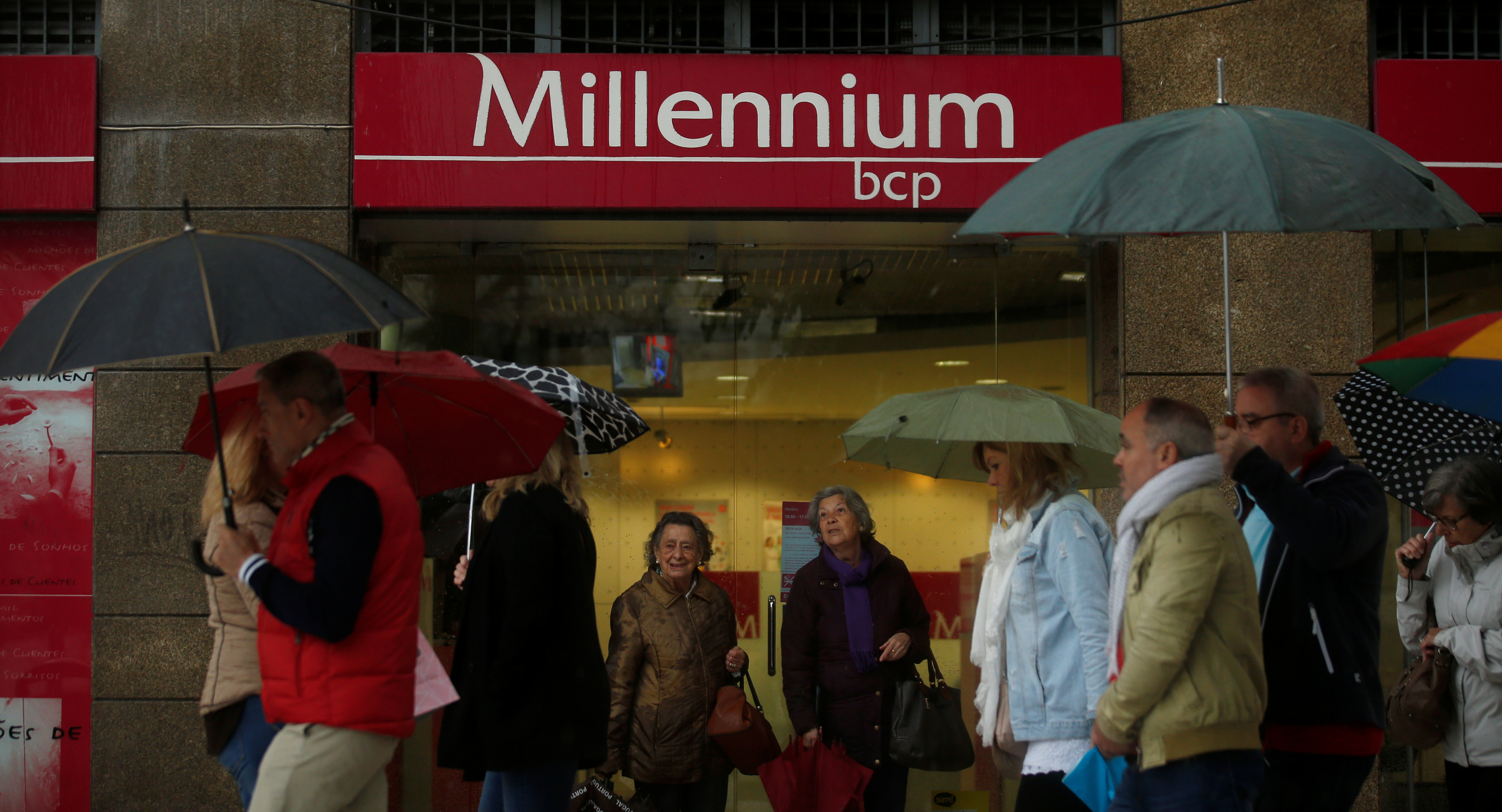People walk near a branch of Millennium BCP Bank in downtown Lisbon