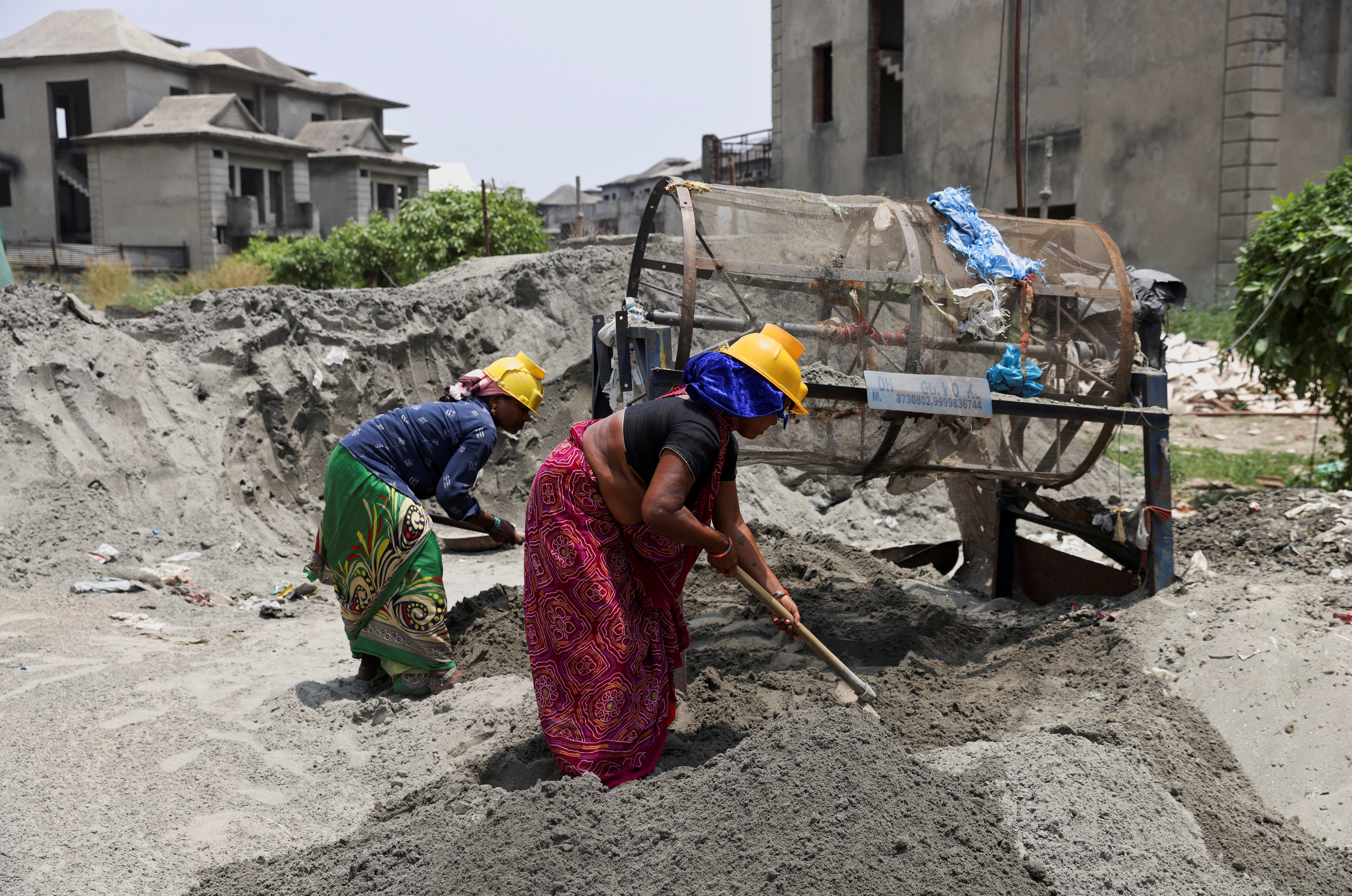 Labourers work at a construction site on a hot summer day, in Noida
