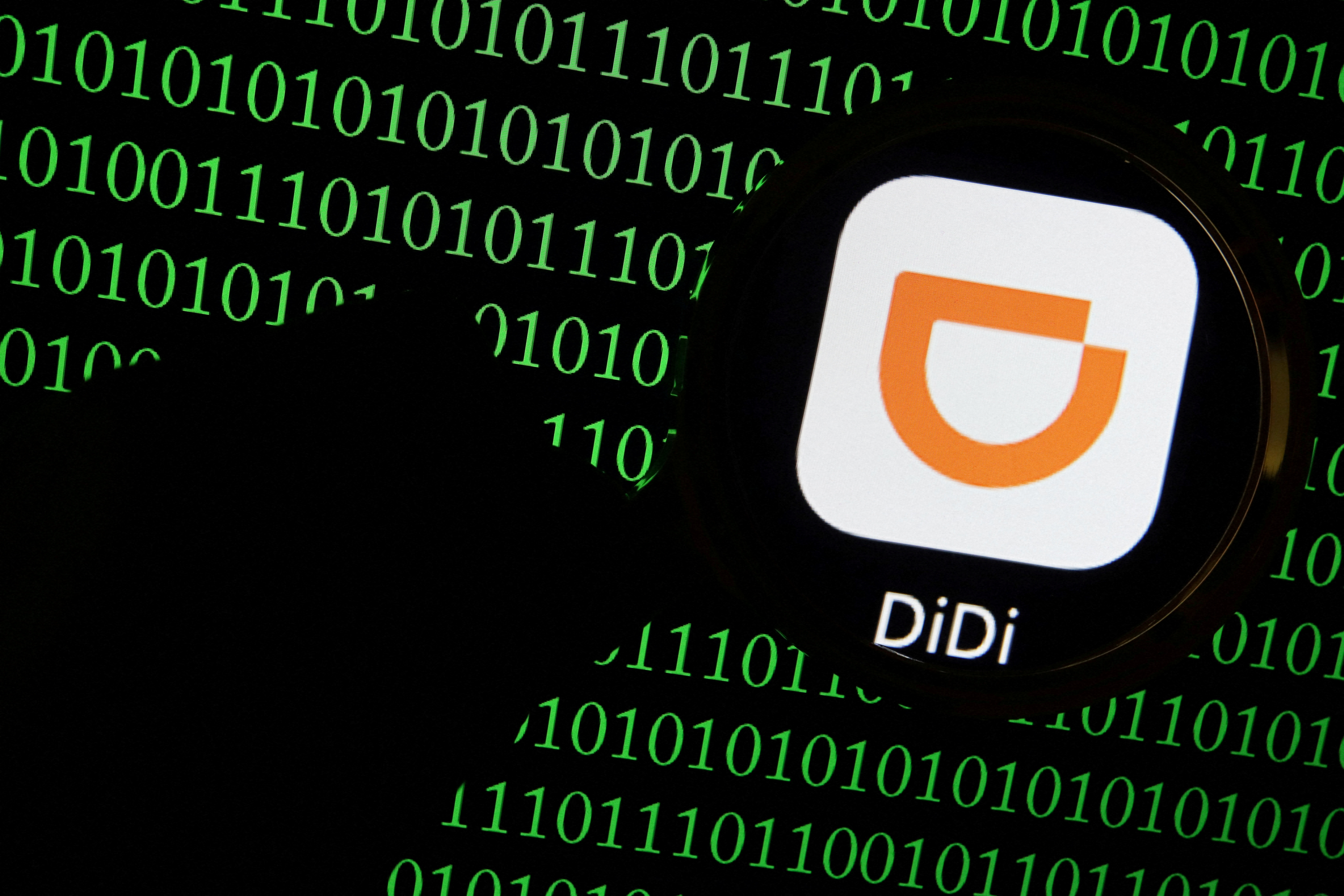 The app logo of Chinese ride-hailing giant Didi is seen through a magnifying glass on a computer screen showing binary digits in this illustration picture taken July 7, 2021. REUTERS/Florence Lo/Illustration/File Photo