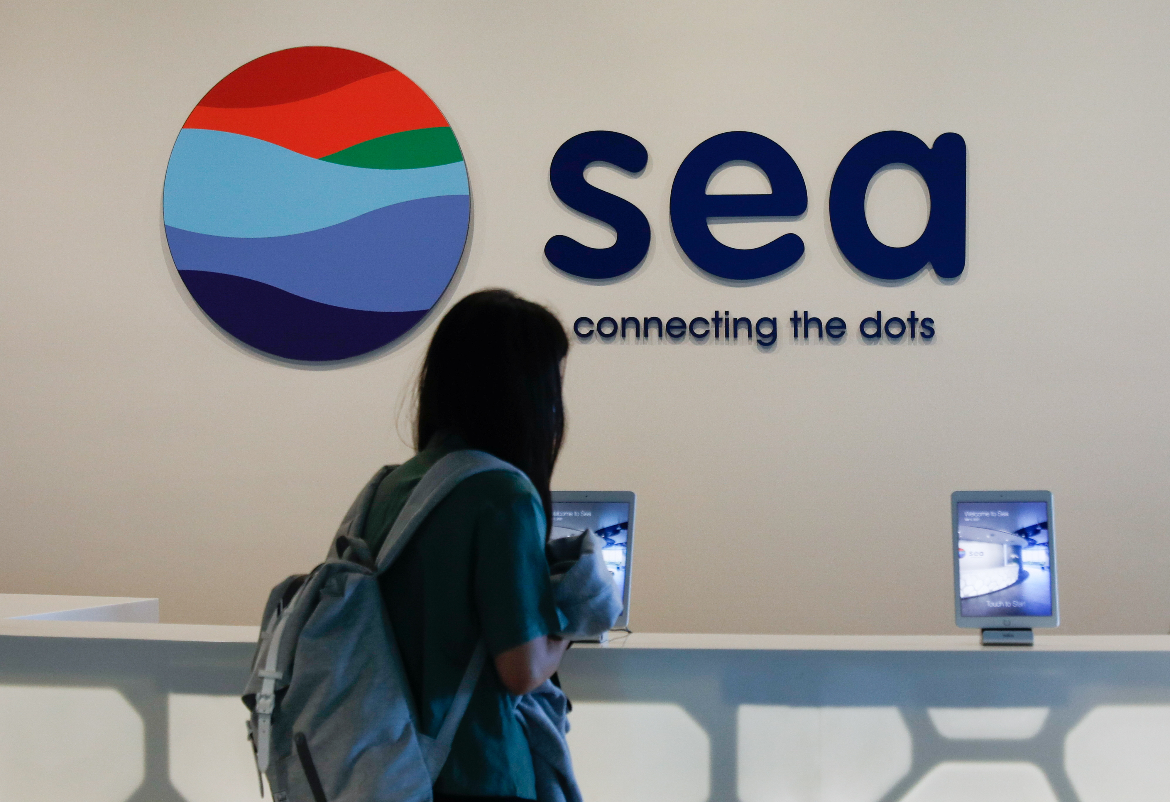 A person stands in front of a signage of Southeast Asian e-commerce and gaming group Sea Ltd's, in Singapore