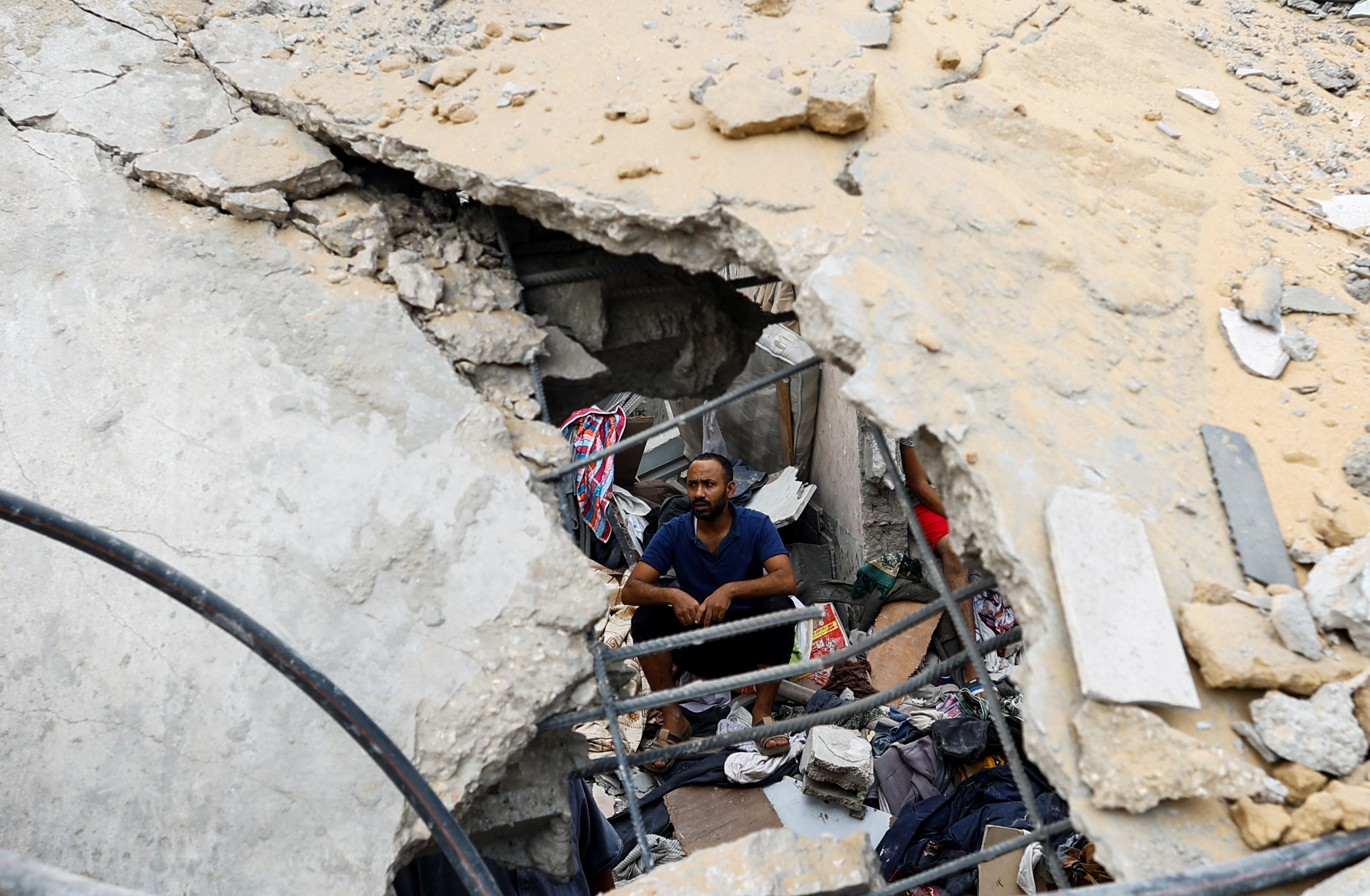 A Palestinian man sits amidst the rubble at the site of Israeli strikes on houses in Khan Younis