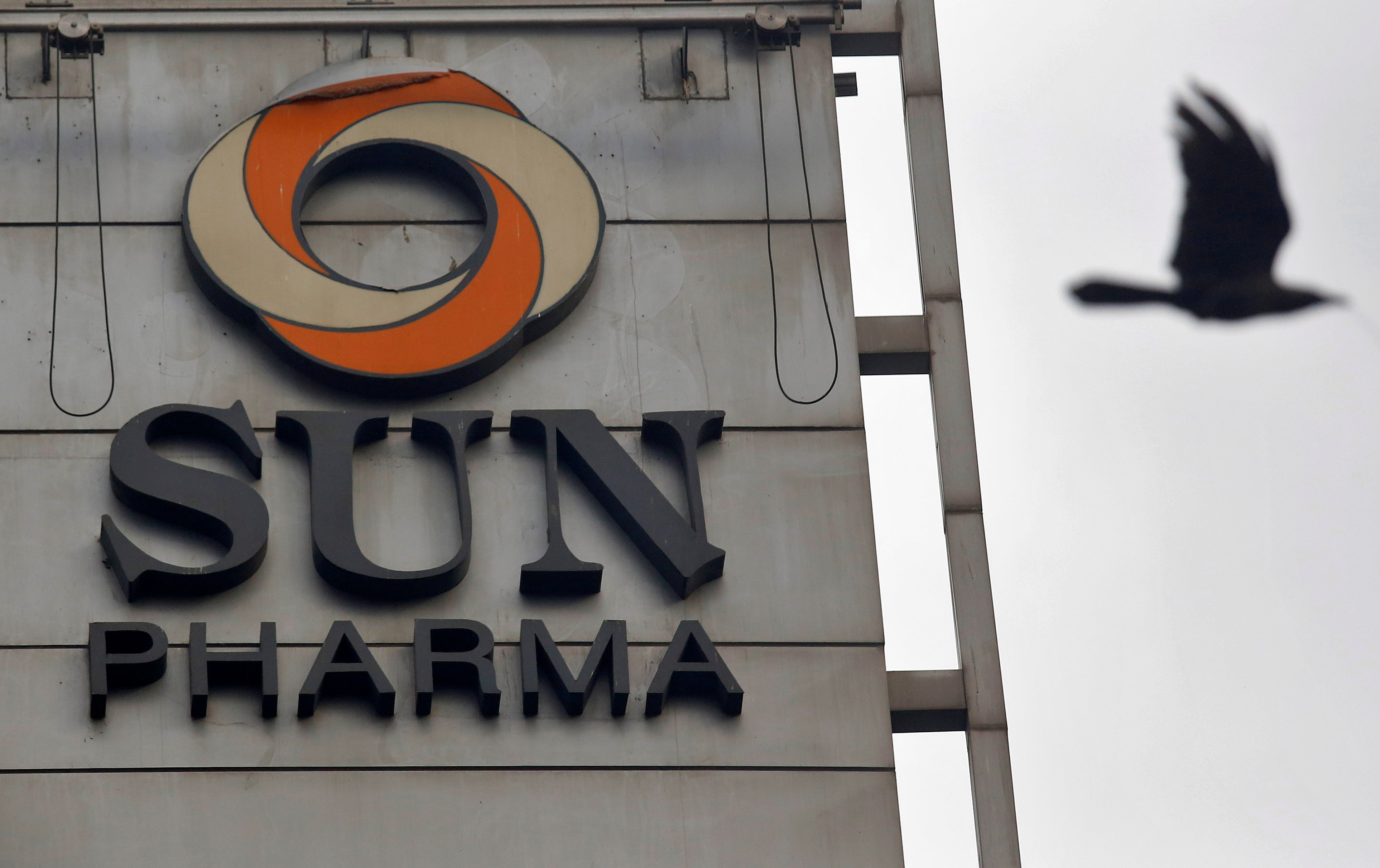 A bird flies past the logo of Sun Pharmaceutical Industries Ltd. installed on the facade of its corporate office in Mumbai