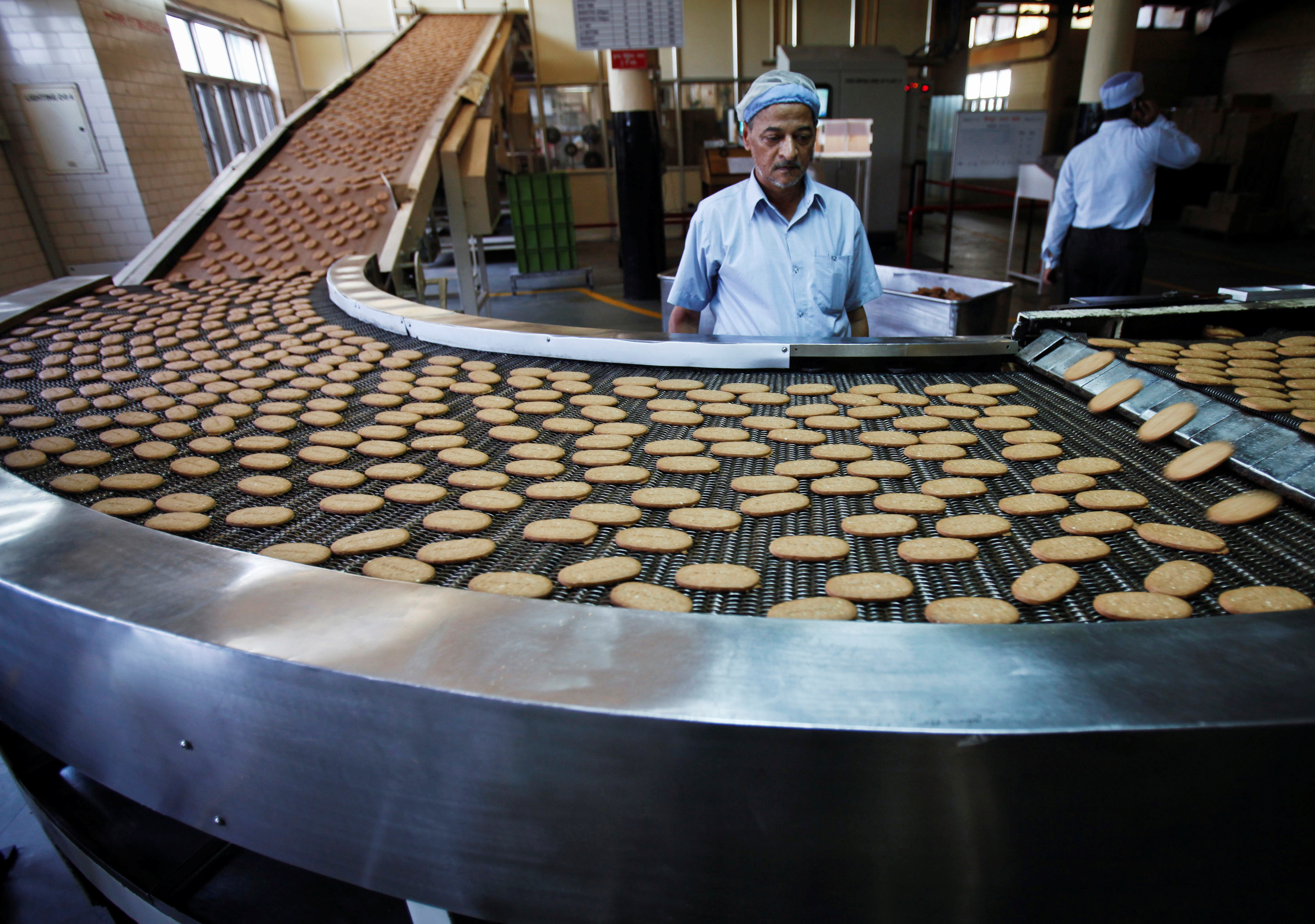 FILE PHOTO A worker stands next to a production line at the Britannia biscuit factory in New Delhi