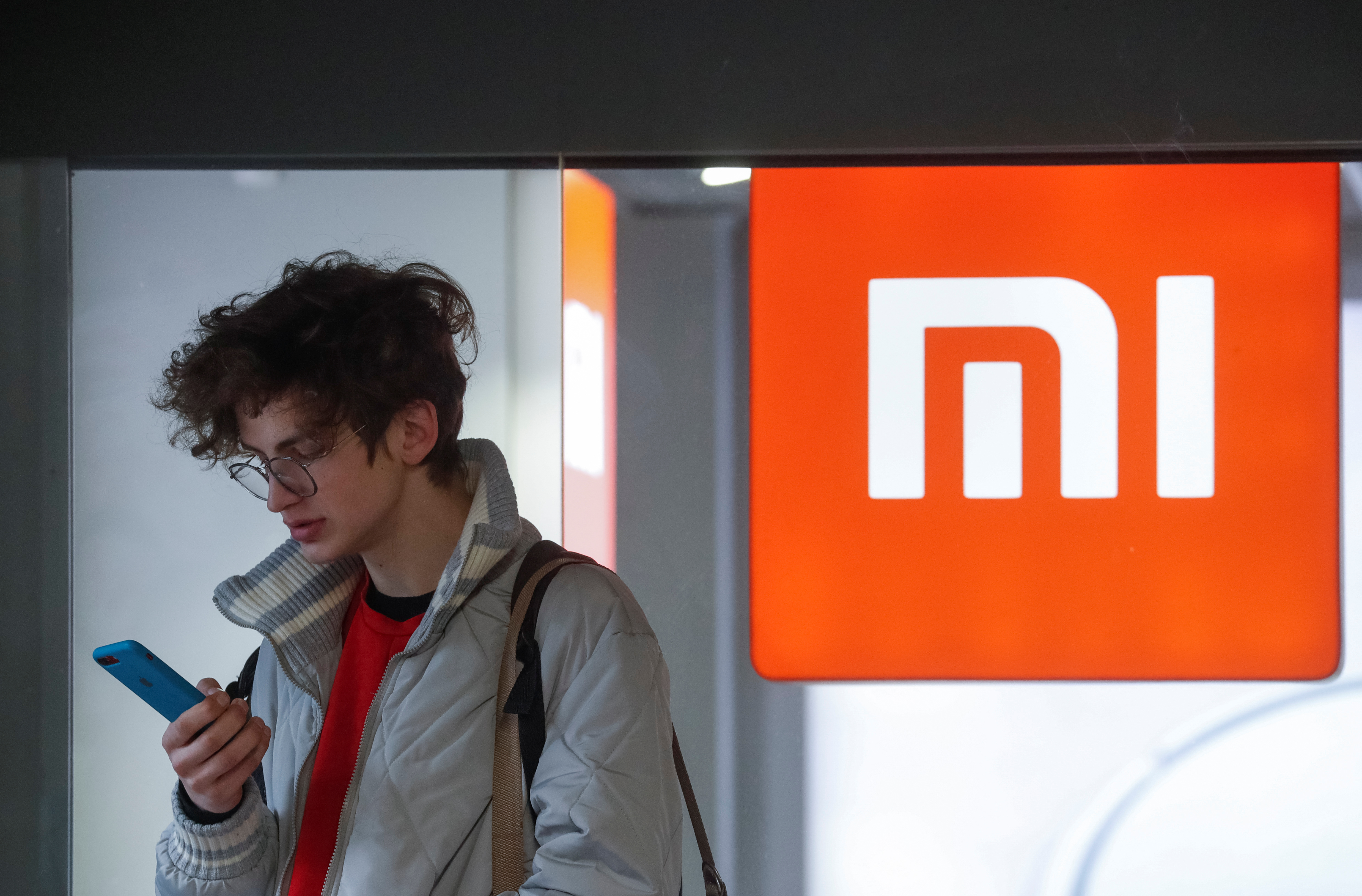 A man uses his smartphone next to the Xiaomi brand's store in central Kiev