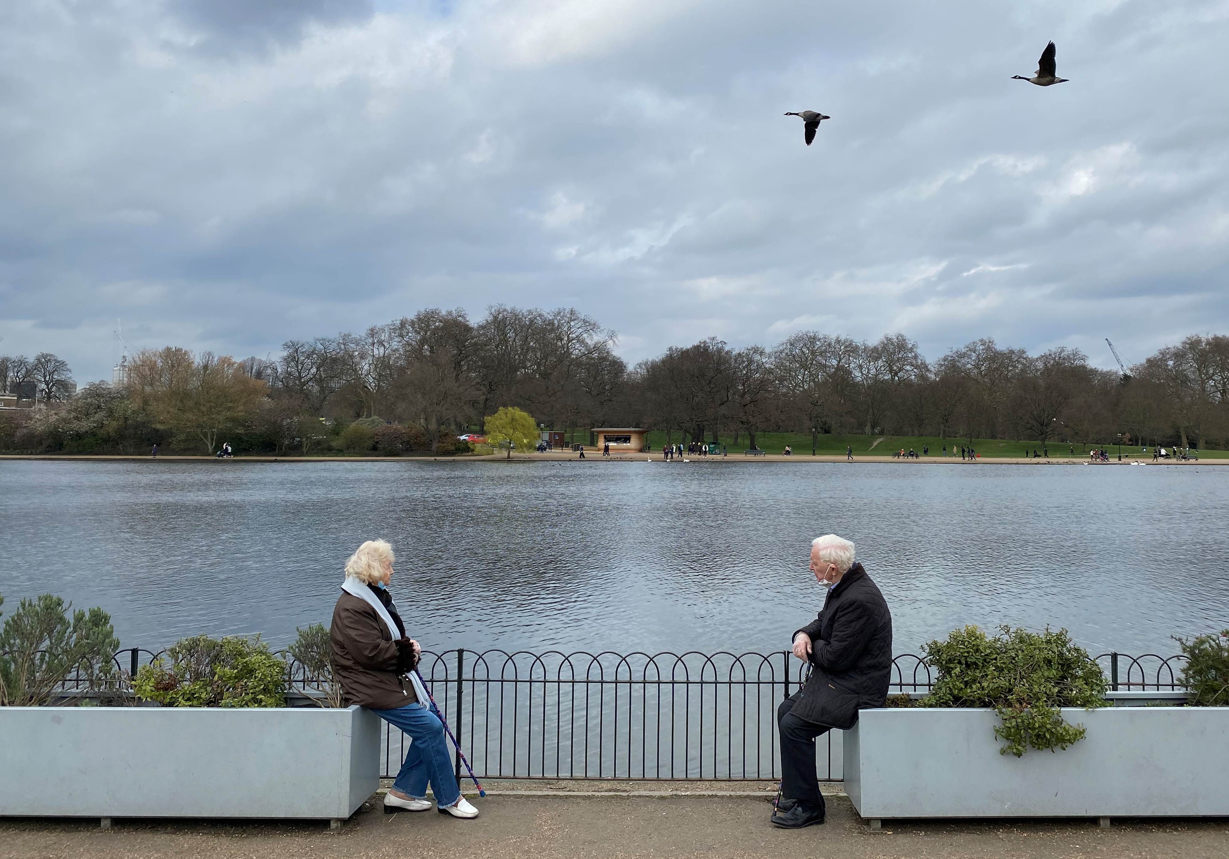 Two people are seen socially-distancing as they chat together in Hyde Park, London