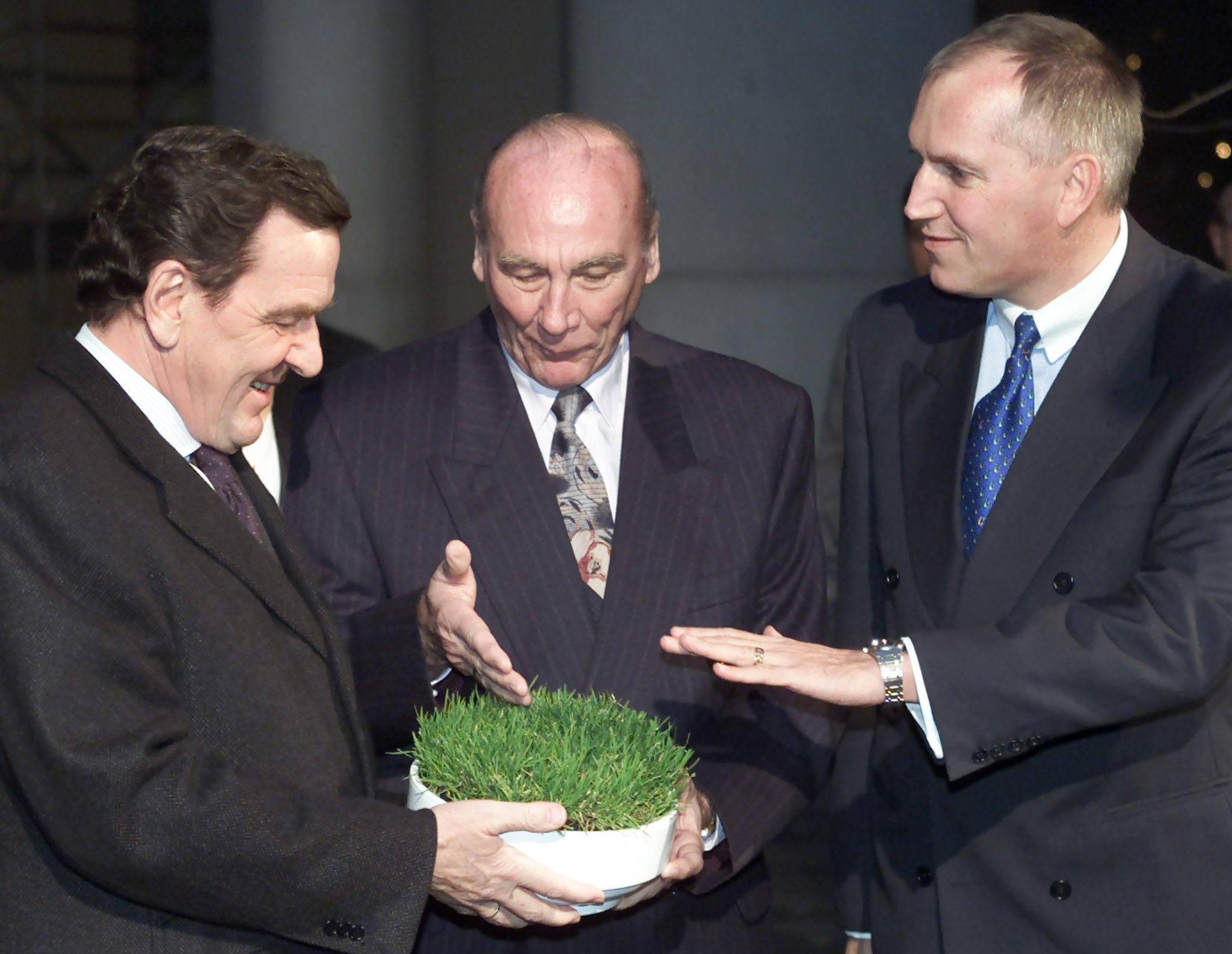 Swiss ambassador Thomas Borer and former German soccer player Horst Eckel (C) present Germany's Chancellor Gerhard Schroeder a piece of green of the seize of an A4 paper from the Bern Wankdorf stadium in Berlin December 12, 2001.  REUTERS/Tobias Schwarz
