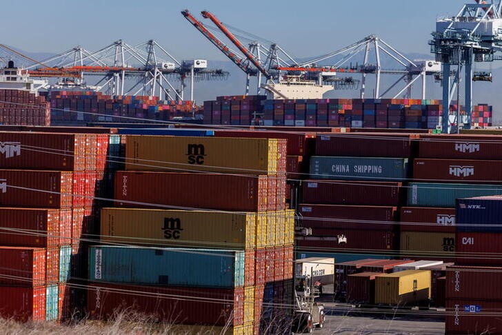Stacked containers are shown as ships unload their cargo at the Port of Los Angeles