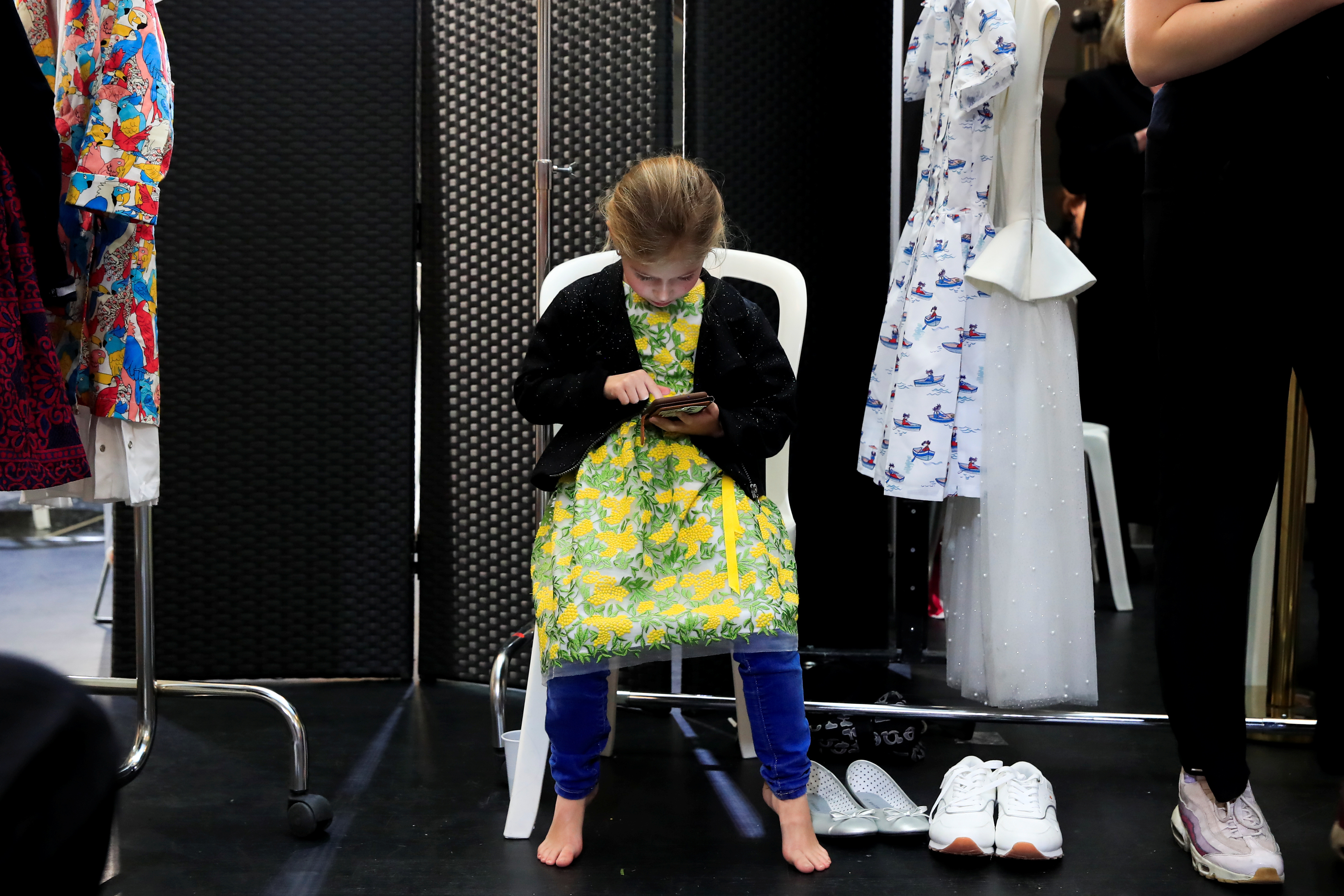 A girl looks at a mobile phone backstage before a show during Kids Fashion Week Paris in Paris
