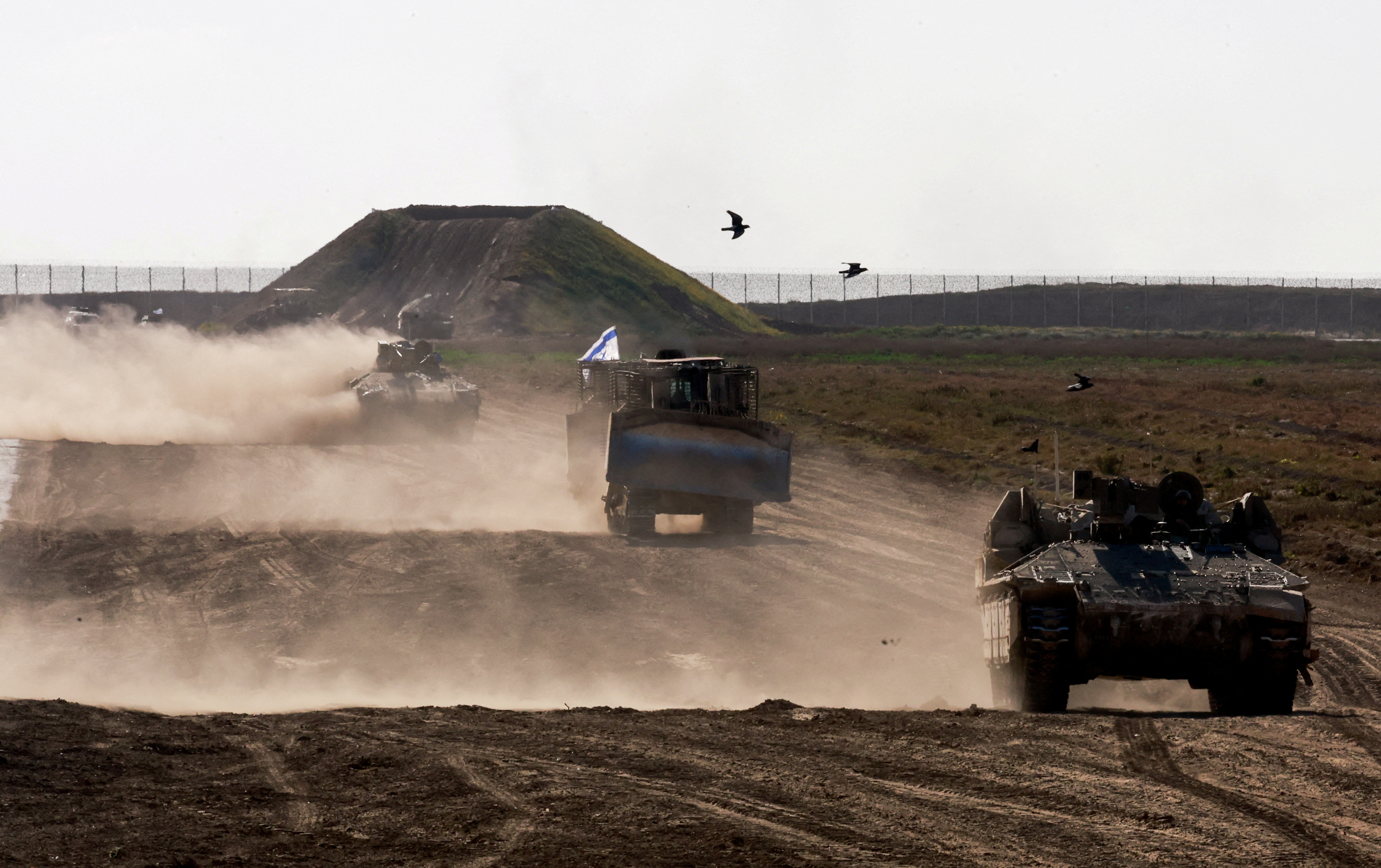 Military vehicles maneuvre near the Israel-Gaza border fence, in Israel