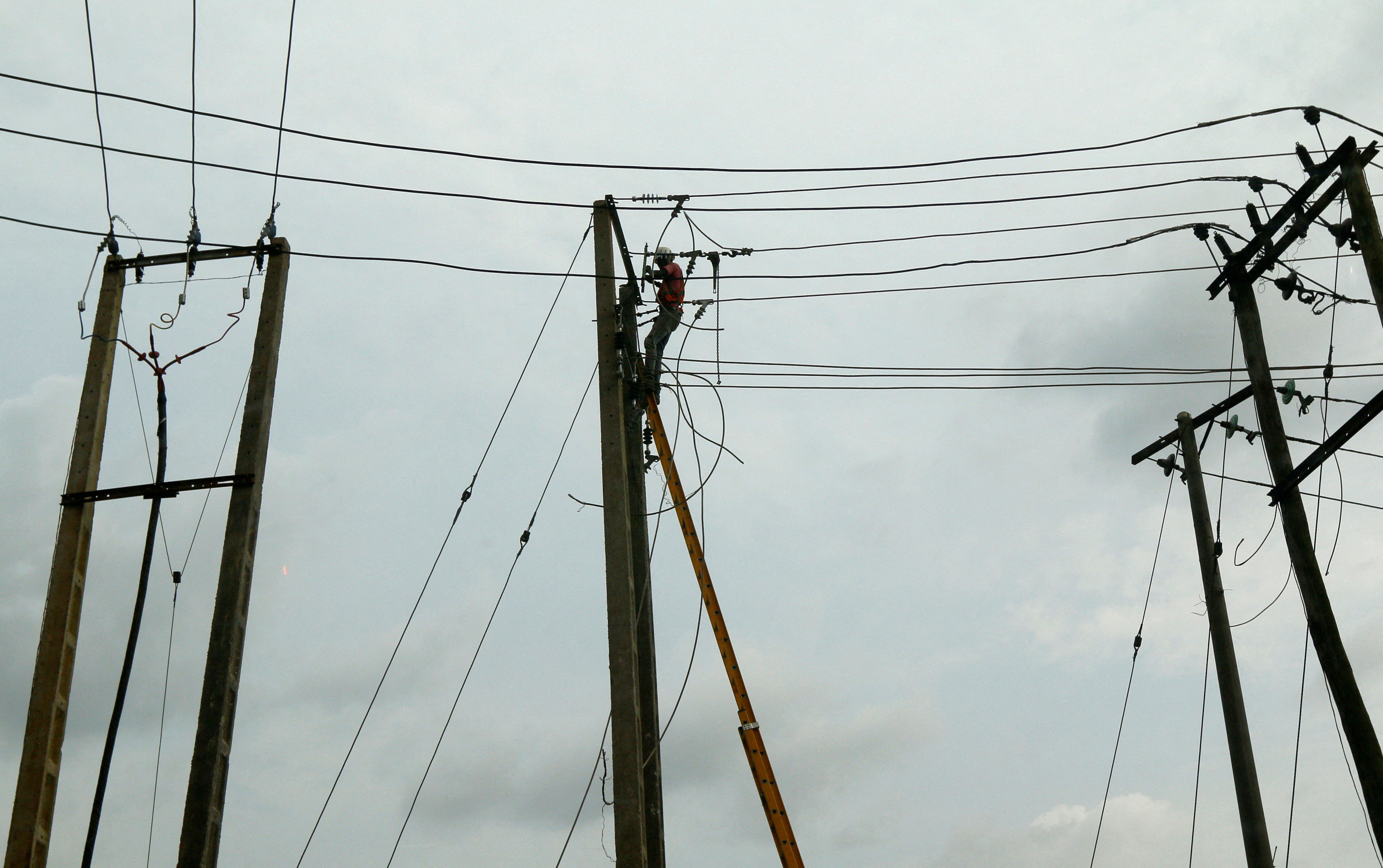 A power labourer fixes electric cables on a pole in Ojodu district in Lagos
