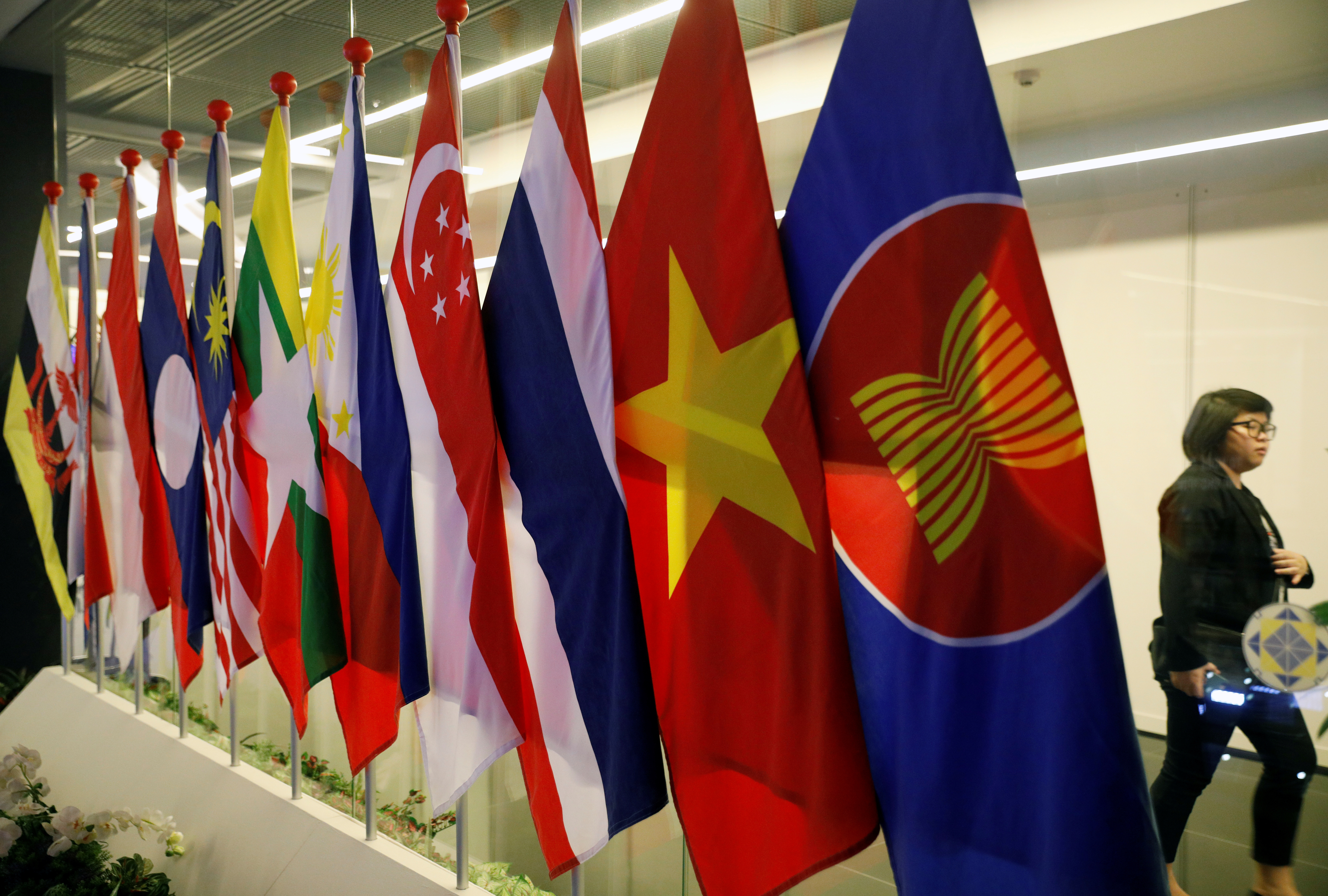 A woman passes ASEAN Summit flags at Suntec Convention Centre in Singapore
