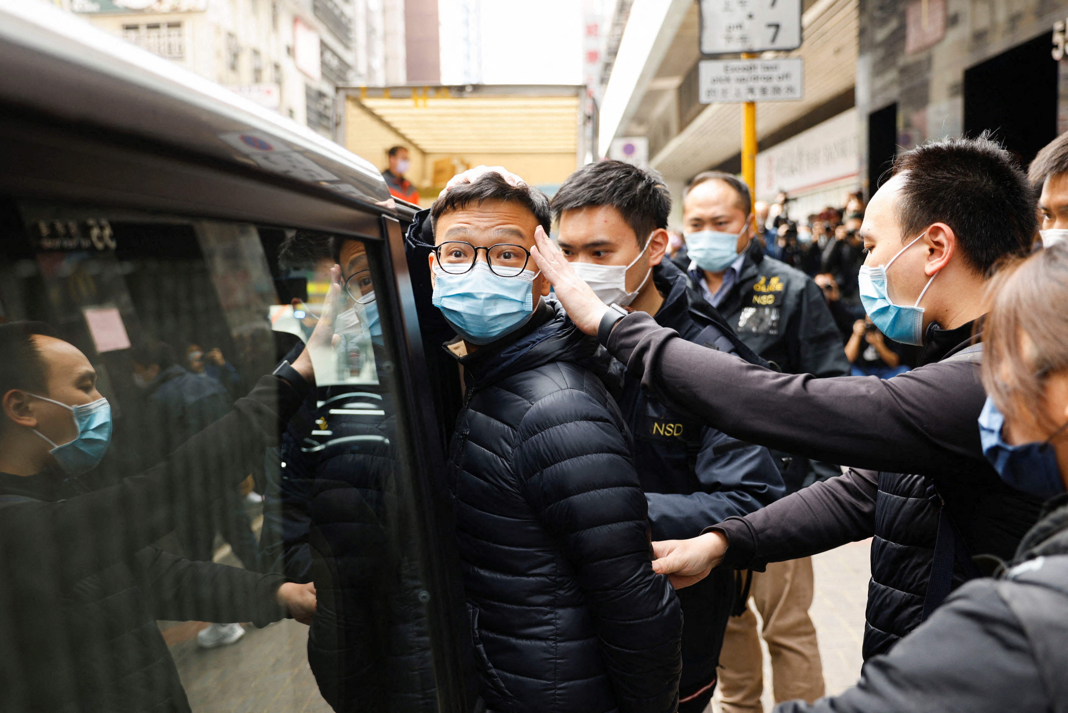 Stand News acting chief editor Patrick Lam is escorted by police as they leave after the police searched his office in Hong Kong