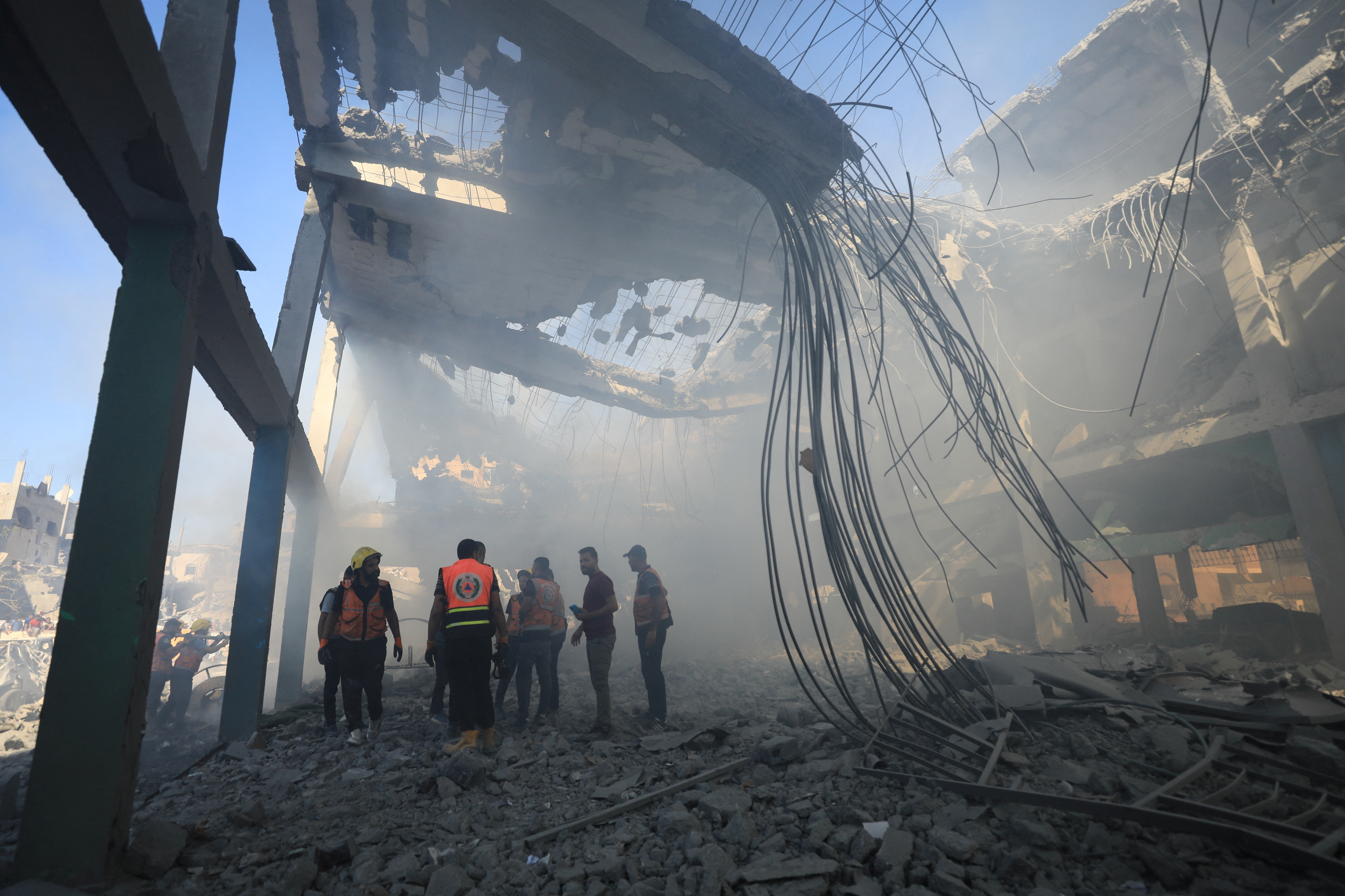 Palestinians inspect the site of an Israeli strike on a college sheltering displaced people, in the northern Gaza Strip