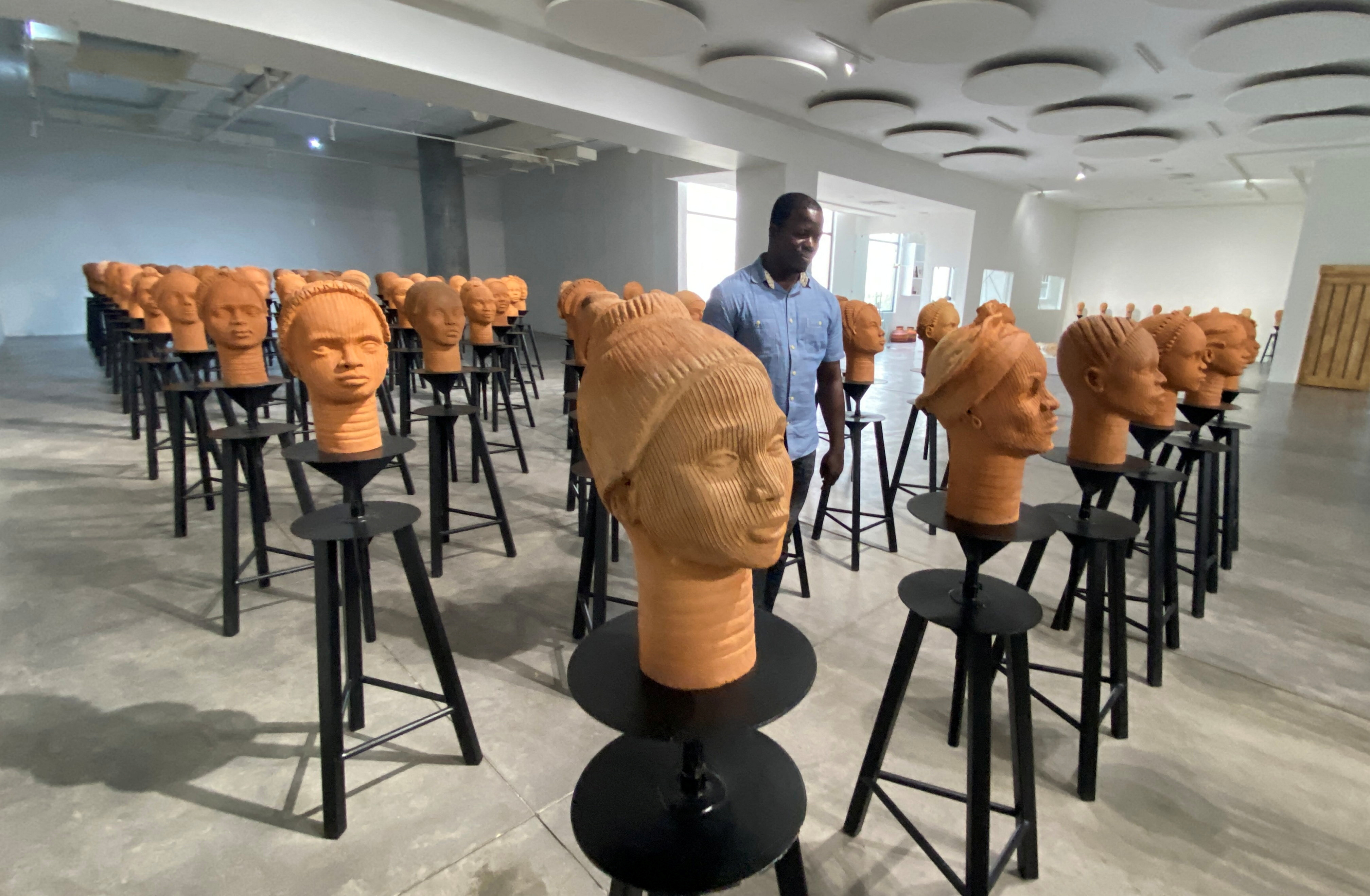 A man walks across a set up of terra cotta heads, a French woman collection representing the remaining Chibok school girls in captivity in Lagos
