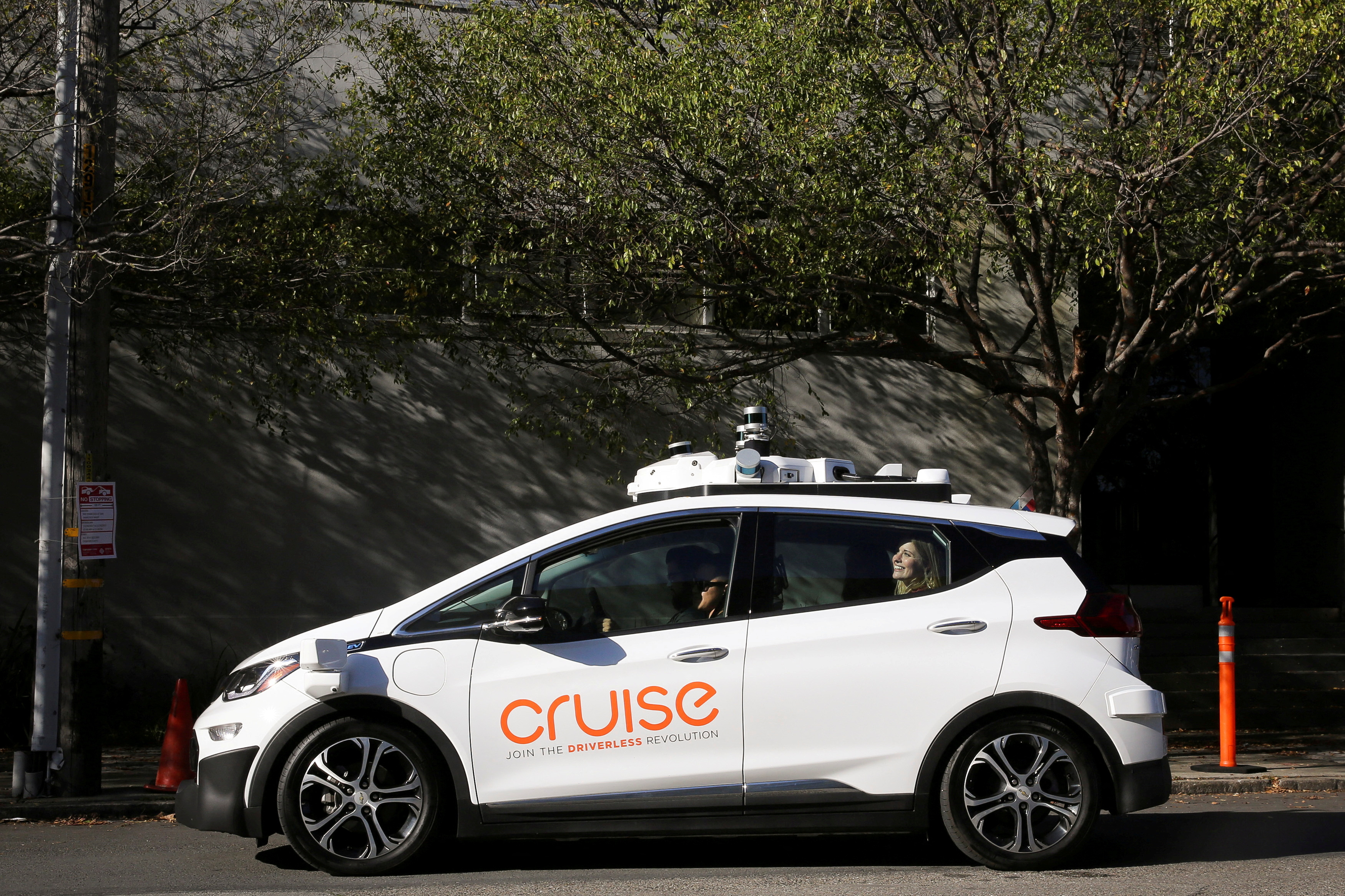 A woman smiles in the back seat of a self-driving Chevy Bolt EV car during a media event by Cruise, GM’s autonomous car unit,  in San Francisco