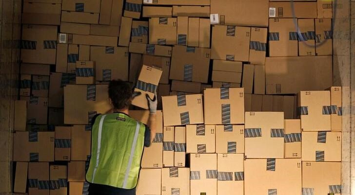 Worker stacks a shipping trailer with boxed items for delivery at Amazon's distribution center in Phoenix