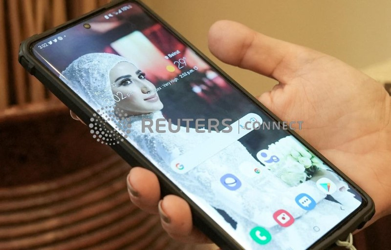Nassma Cheaito holds a mobile phone with her sister Liliane Cheaito's picture as a wallpaper, in Beirut