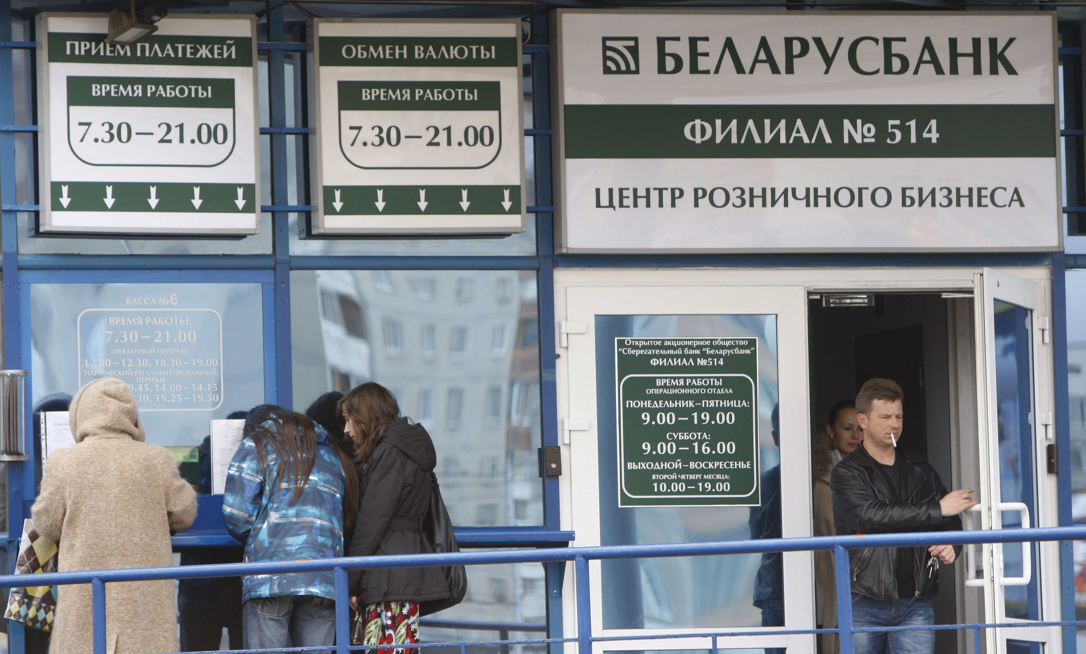 People wait outside the currency exchange office of a bank in Minsk