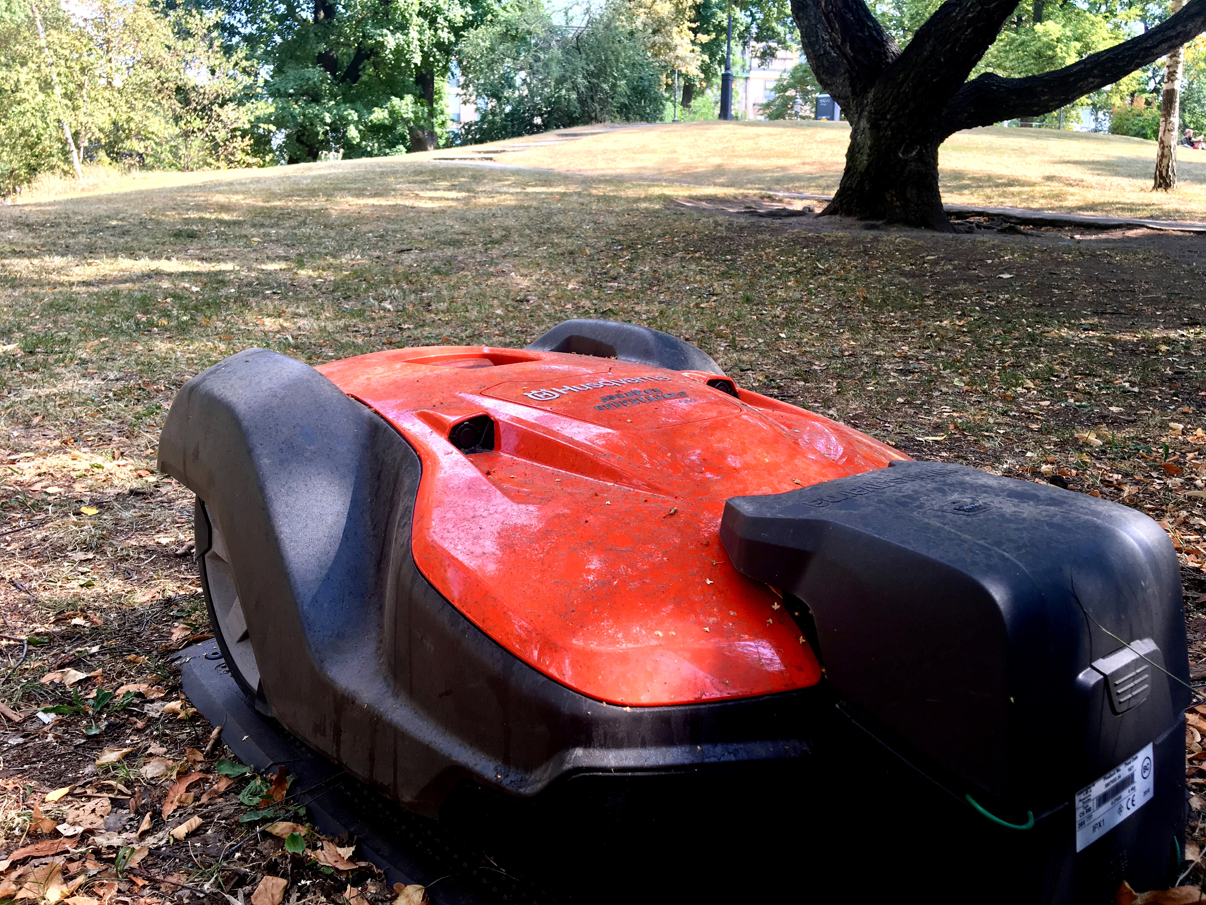 A Husqvarna robotic lawn mower is placed in its docking station in the Humlegarden park in Stockholm