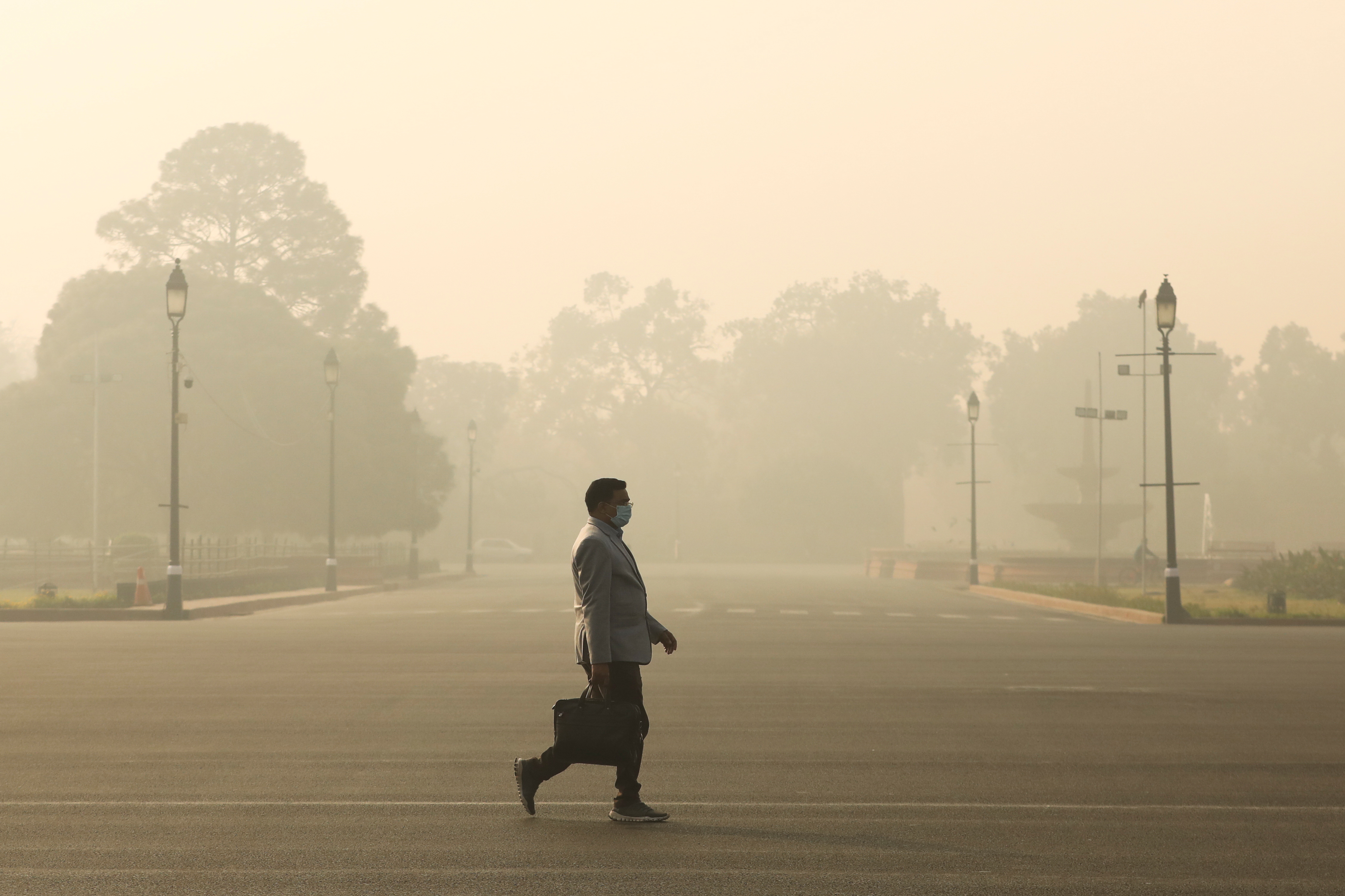 Man walks along a road on a smoggy morning in New Delhi