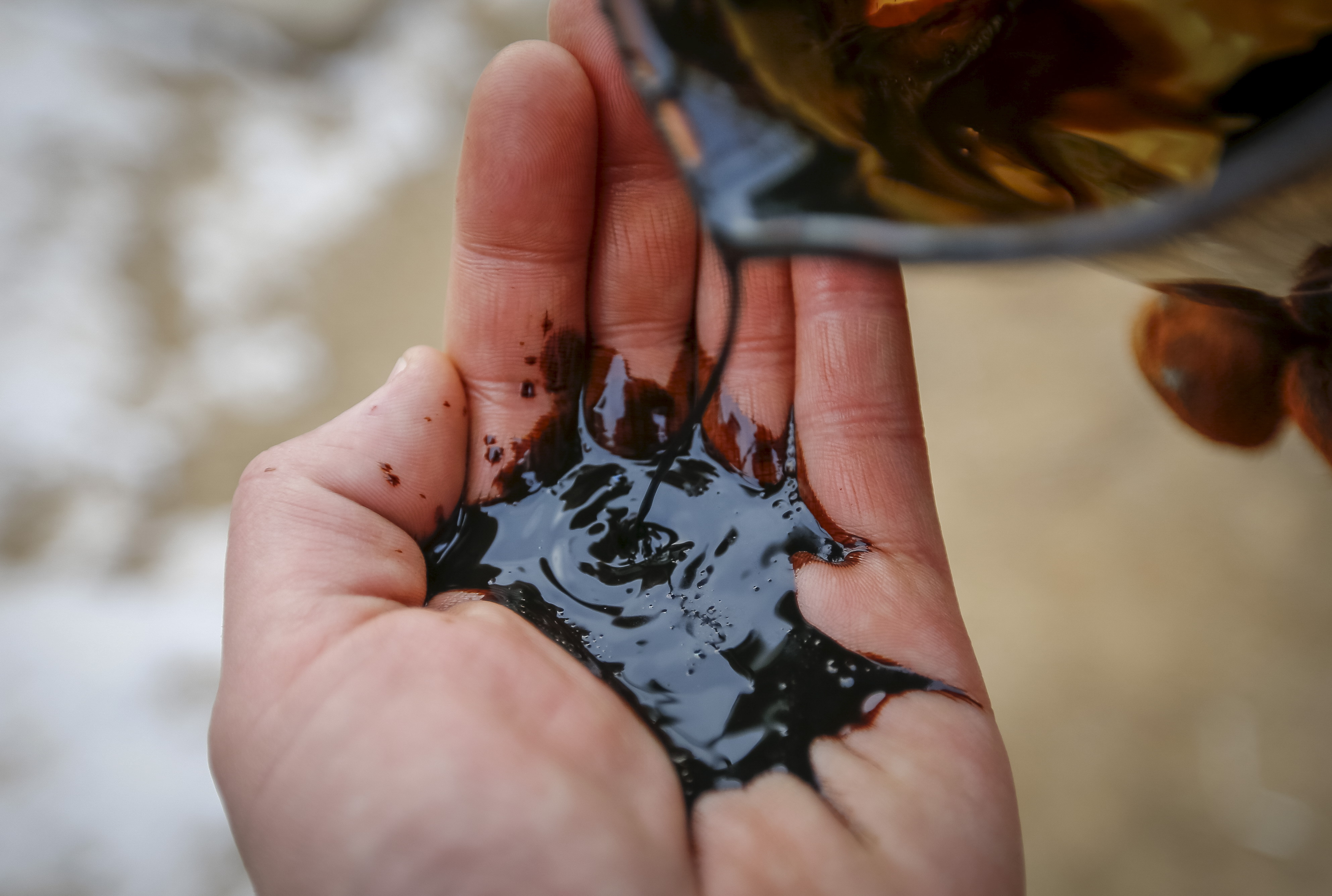A picture illustration shows oil being poured on a palm at oil field in Kyzylorda region, southern Kazakhstan