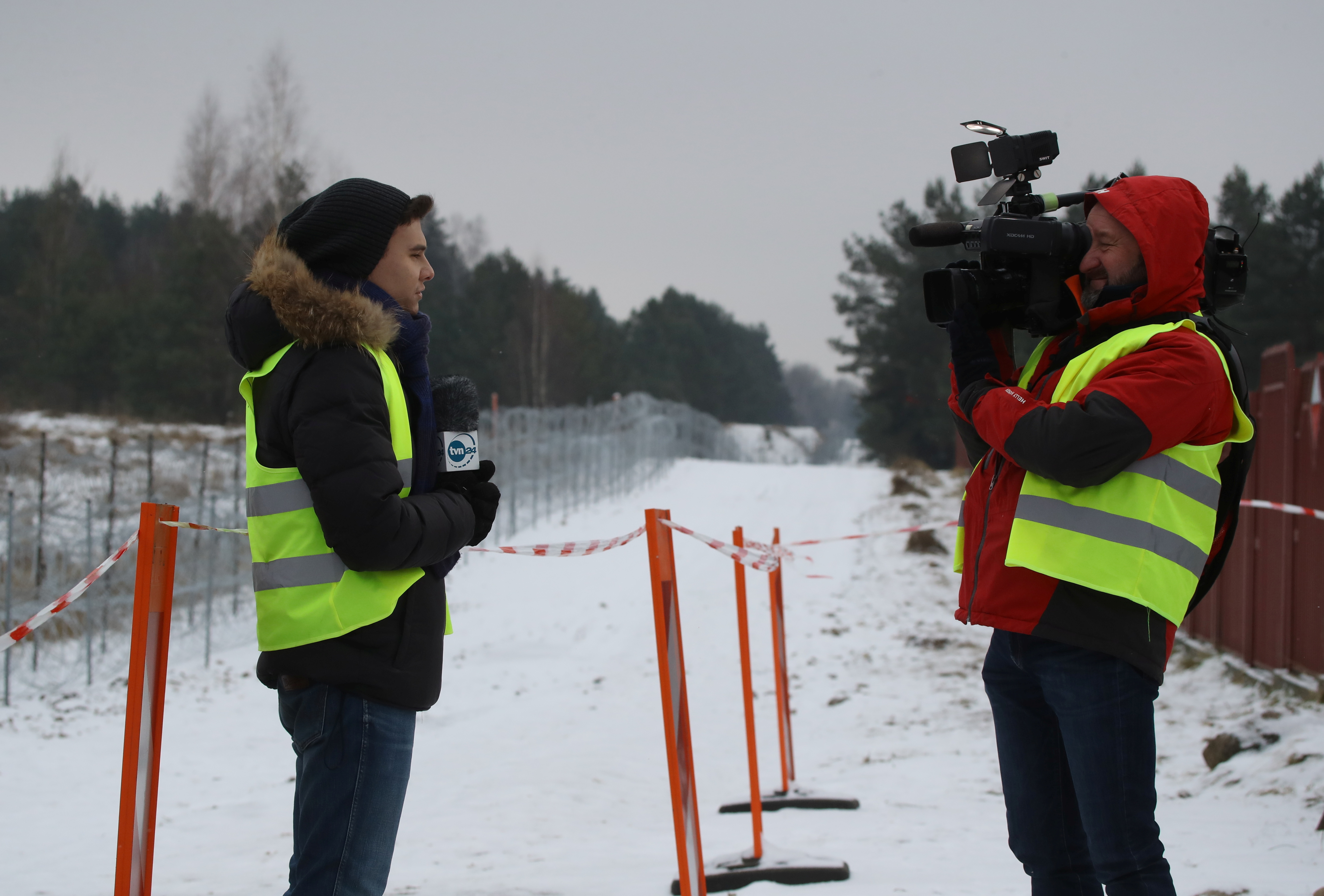Journalists from TVN television record a live report after media representatives were allowed to be present in the border zone, at the Kuznica-Bruzgi checkpoint on the Polish-Belarusian border amid the migrant crisis, in Kuznica, Poland, December 6, 2021. REUTERS/Kacper Pempel