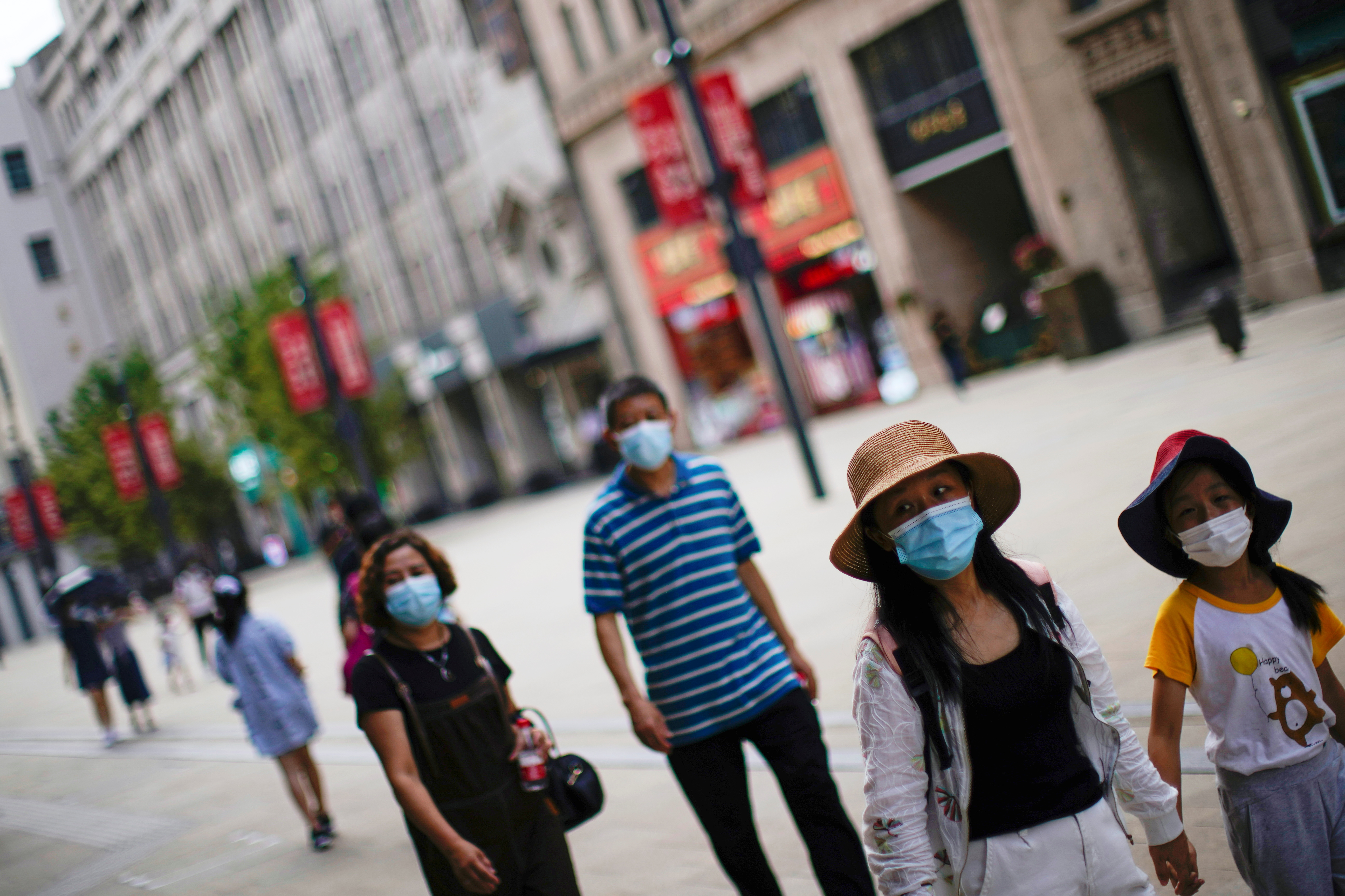 People wearing protective face masks walk on a street, following new cases of the coronavirus disease (COVID-19), in Shanghai, China August 25, 2021. REUTERS/Aly Song