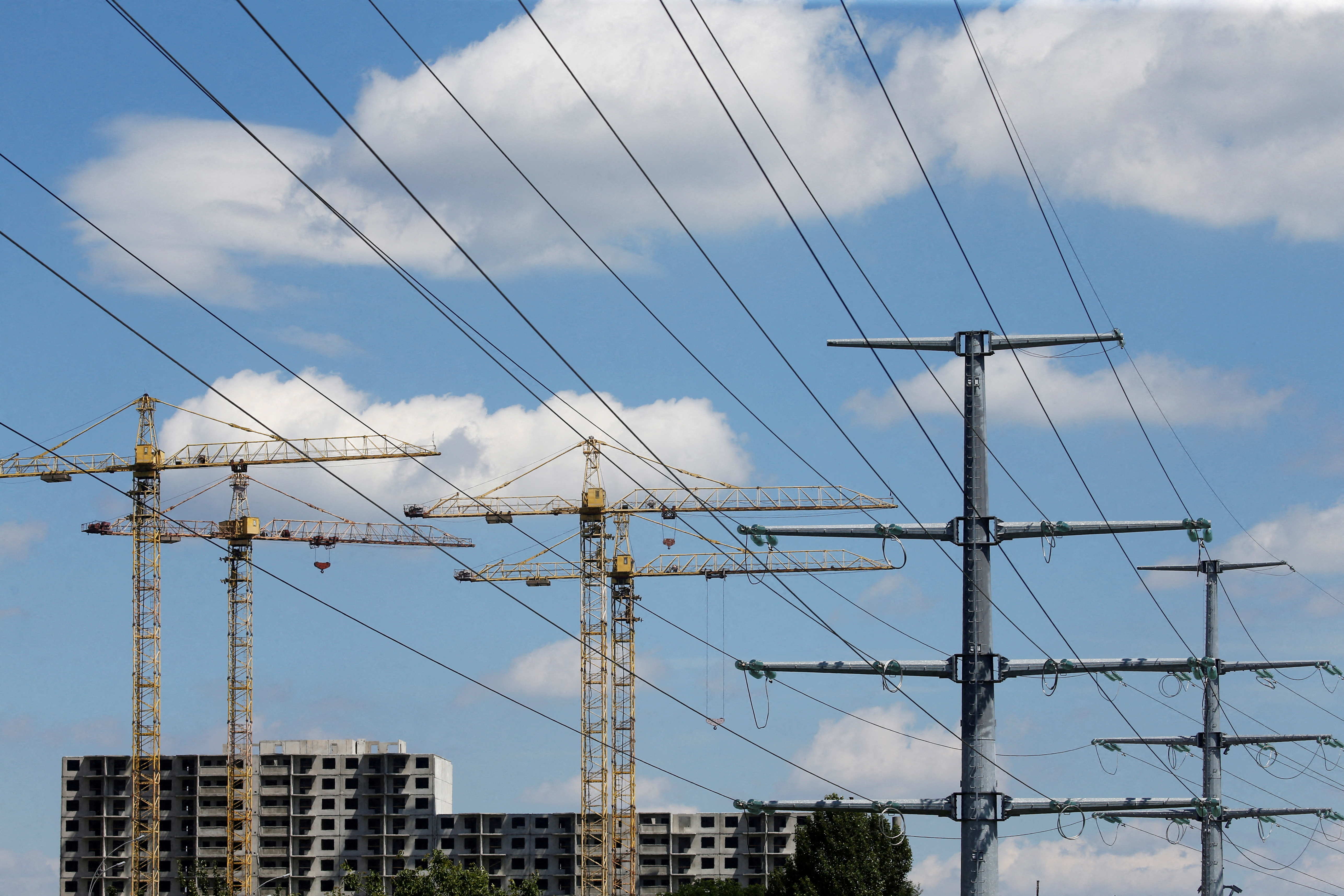 Building cranes and power lines connecting pylons of high-tension electricity are seen in Kyiv
