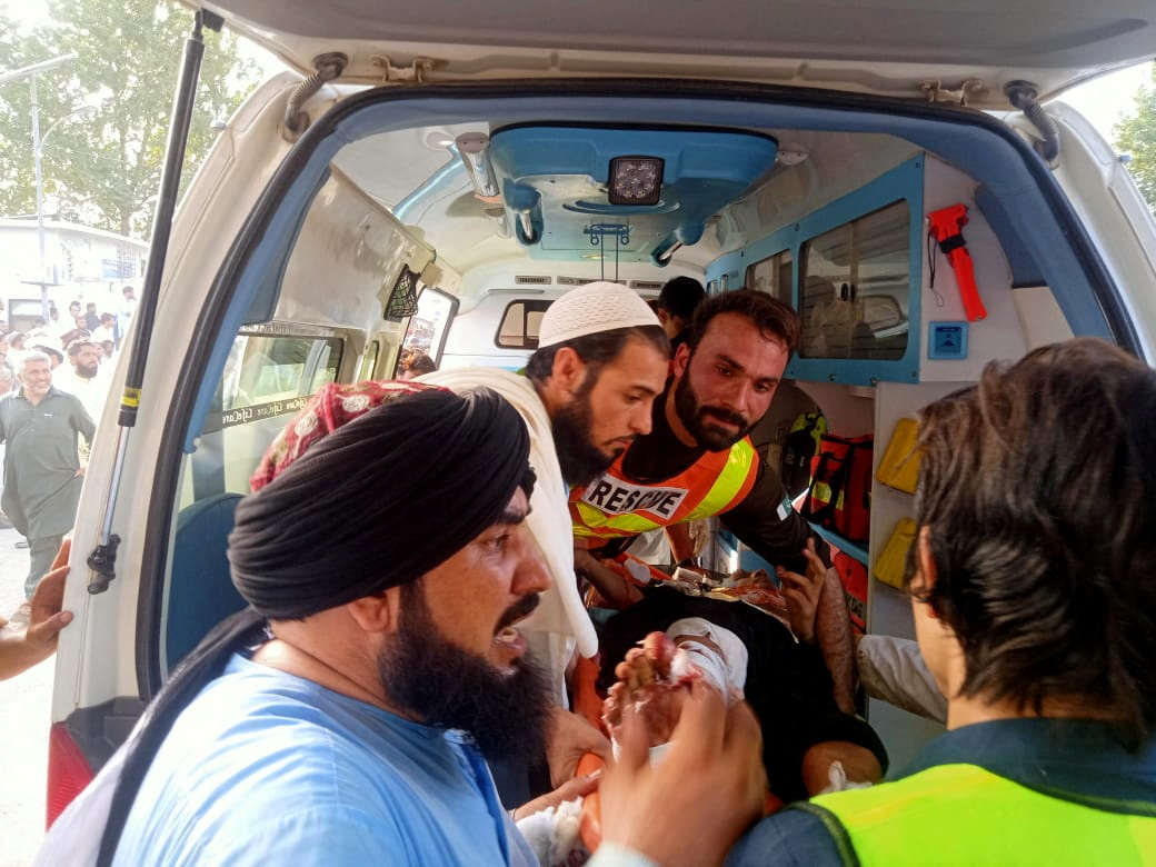 Rescue workers transport injured person to hospital after a blast in Bajaur