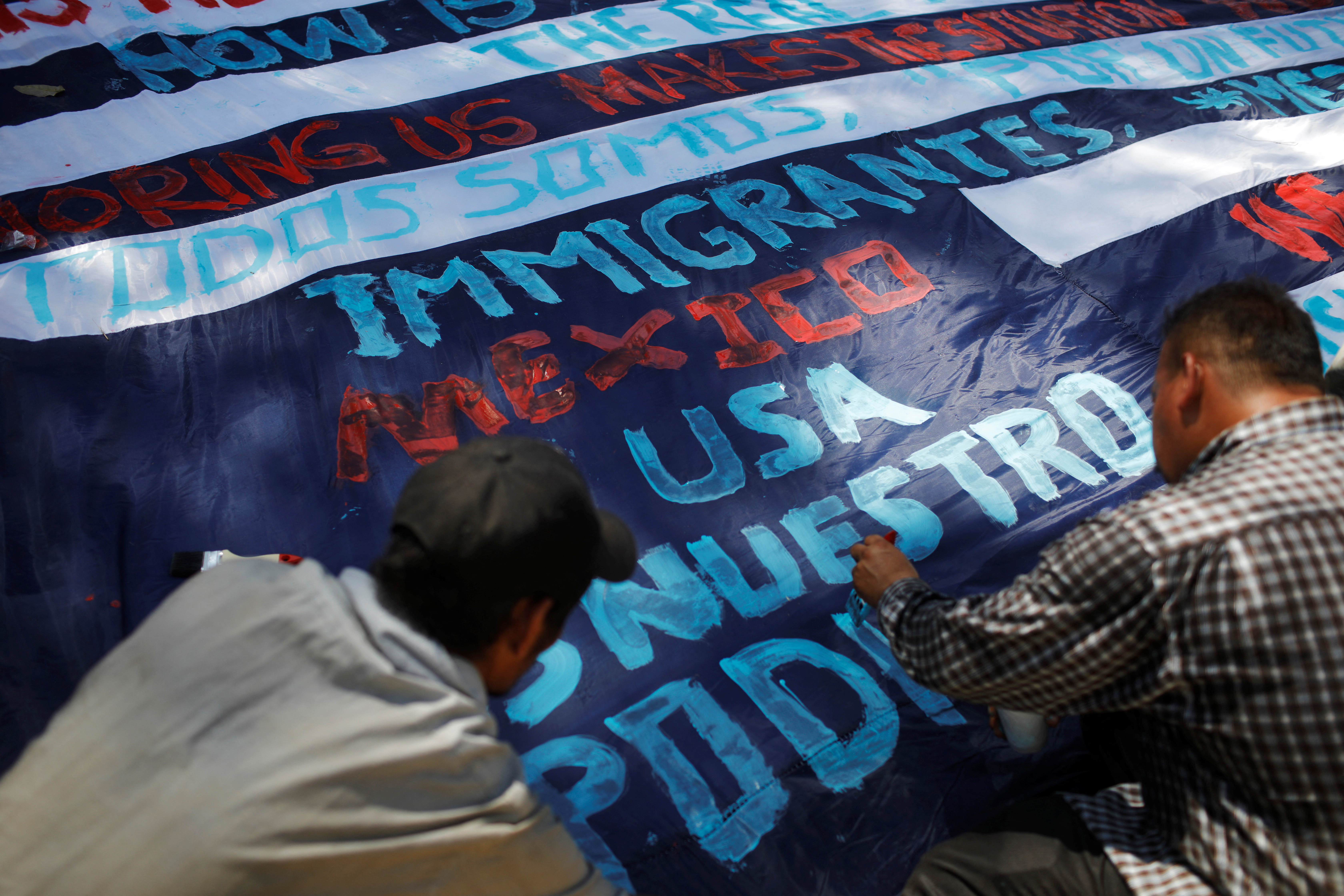 Migrants travelling to the U.S. paint a banner in an improvised shelter in Tecun Uman