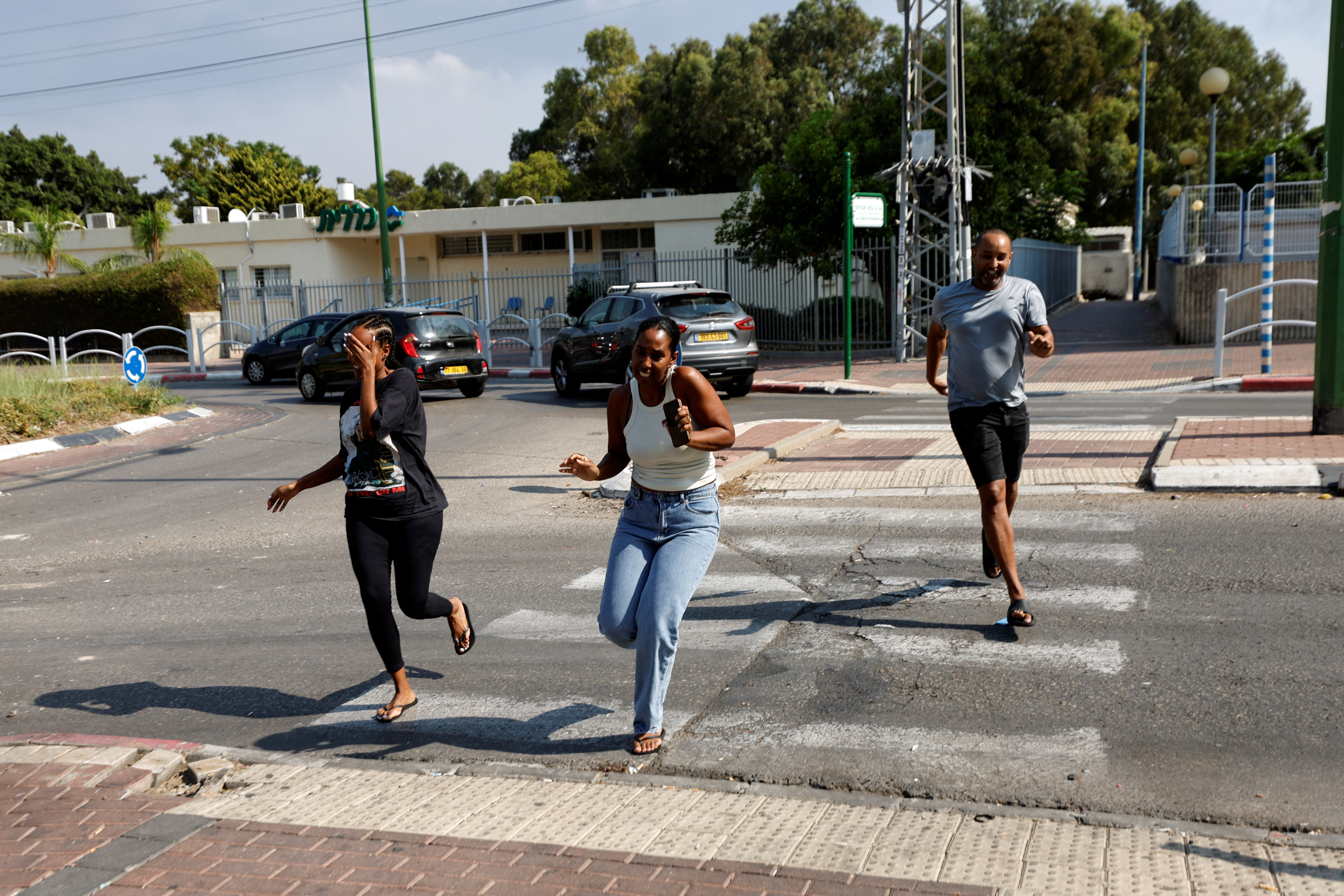 Israelis run for cover while sirens sound as rockets from Gaza are launched towards Israel, in Ashkelon