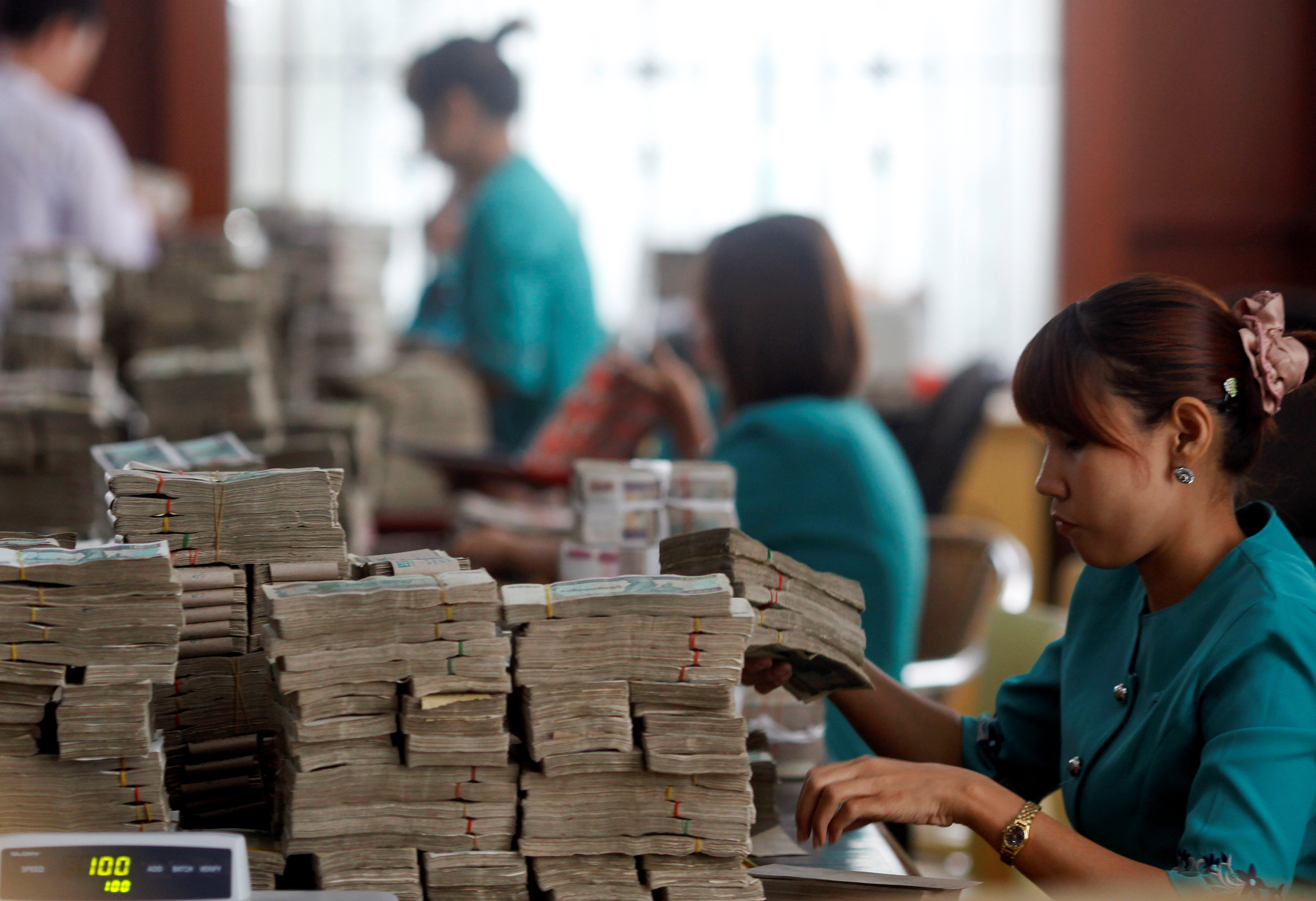 FILE PHOTO: Workers count Myanmar's kyat banknotes at the office of a local bank in Yangon