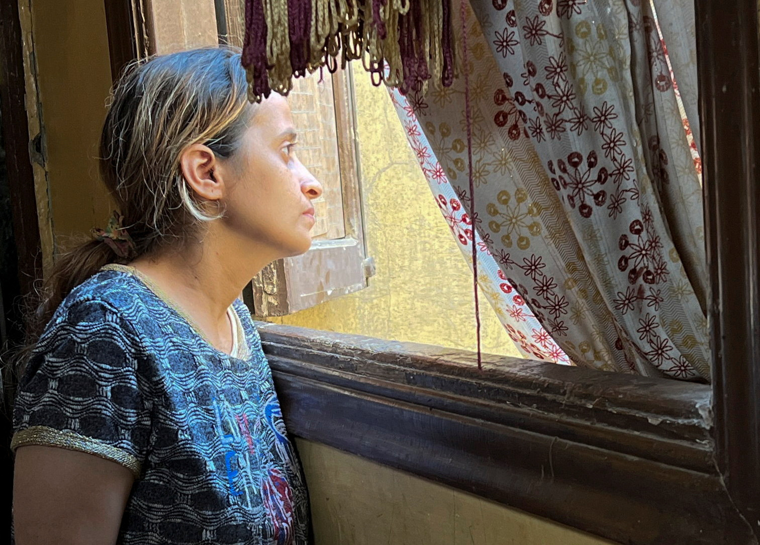 Mary Magdy, a Coptic Christian woman, looks out of a window, in Cairo