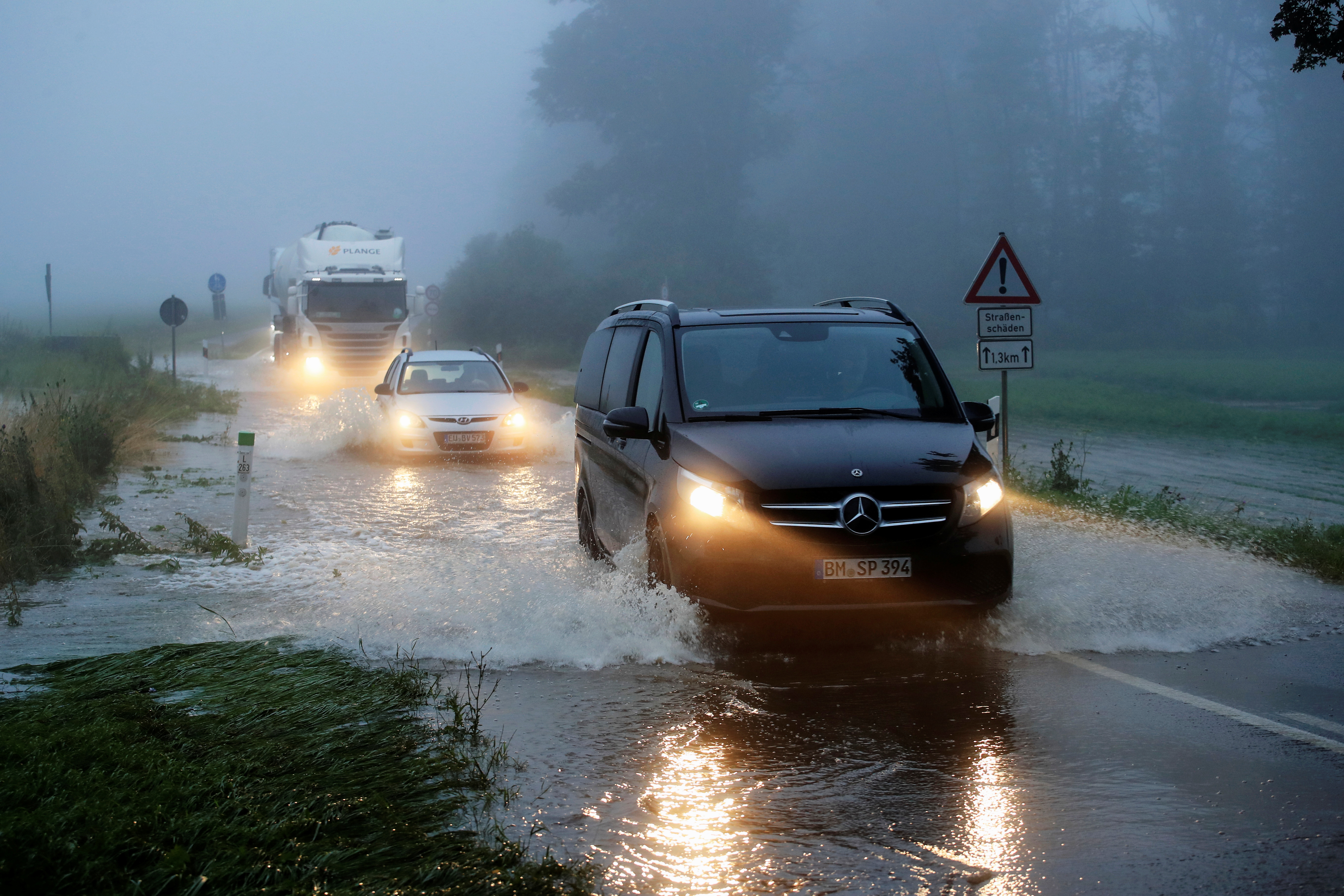 Vehicles travel on a flood affected road after the Erft river swelled following heavy rainfalls in Erftstadt, near Cologne, Germany, July 15, 2021. REUTERS/Wolfgang Rattay