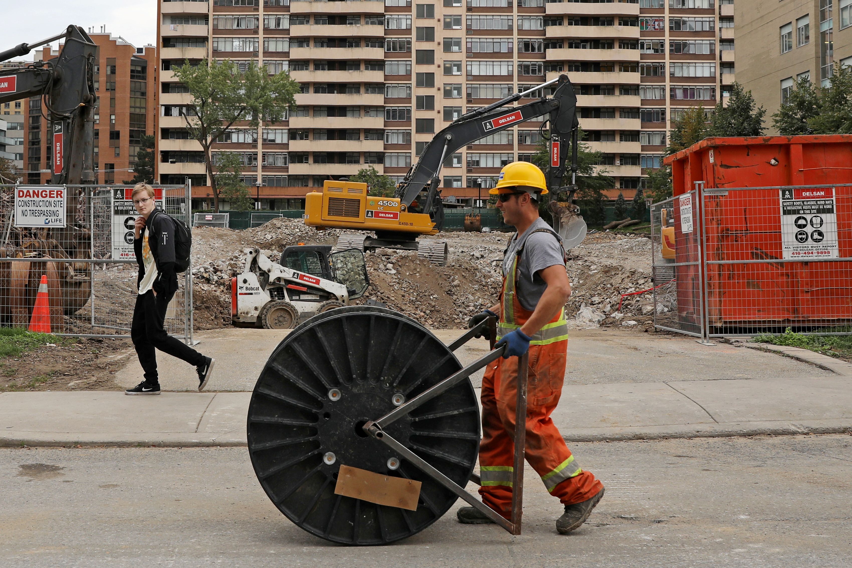 A construction worker passes a condominium site with a roll of cable in Toronto