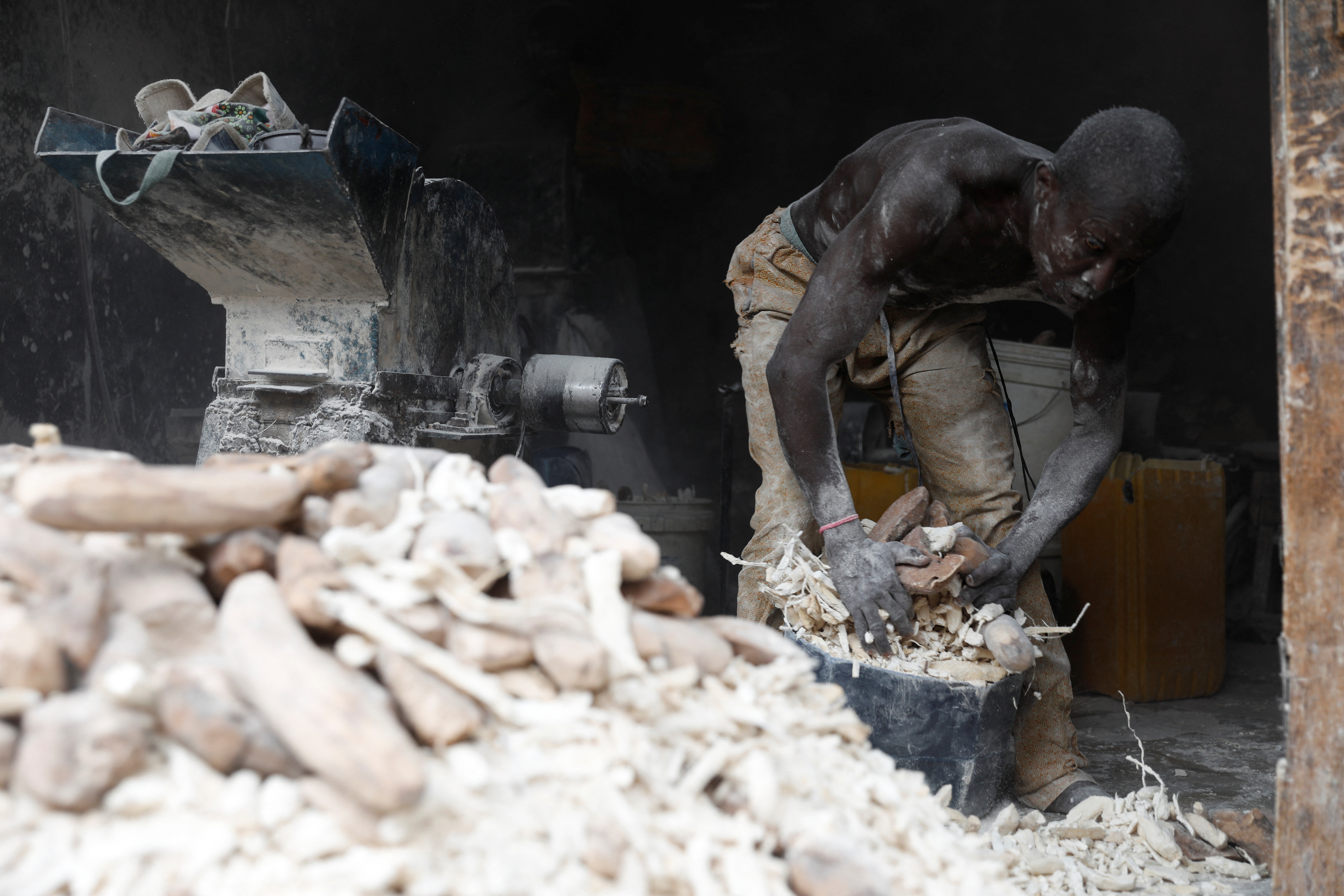 A man heaps dried yam slices as he prepares them for milling, to be processed into yam flour at Bodija market in Ibadan