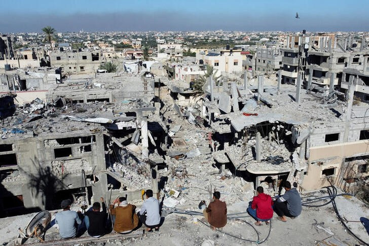 Palestinians look at the houses destroyed in Israeli strikes during the conflict, at Khan Younis refugee camp