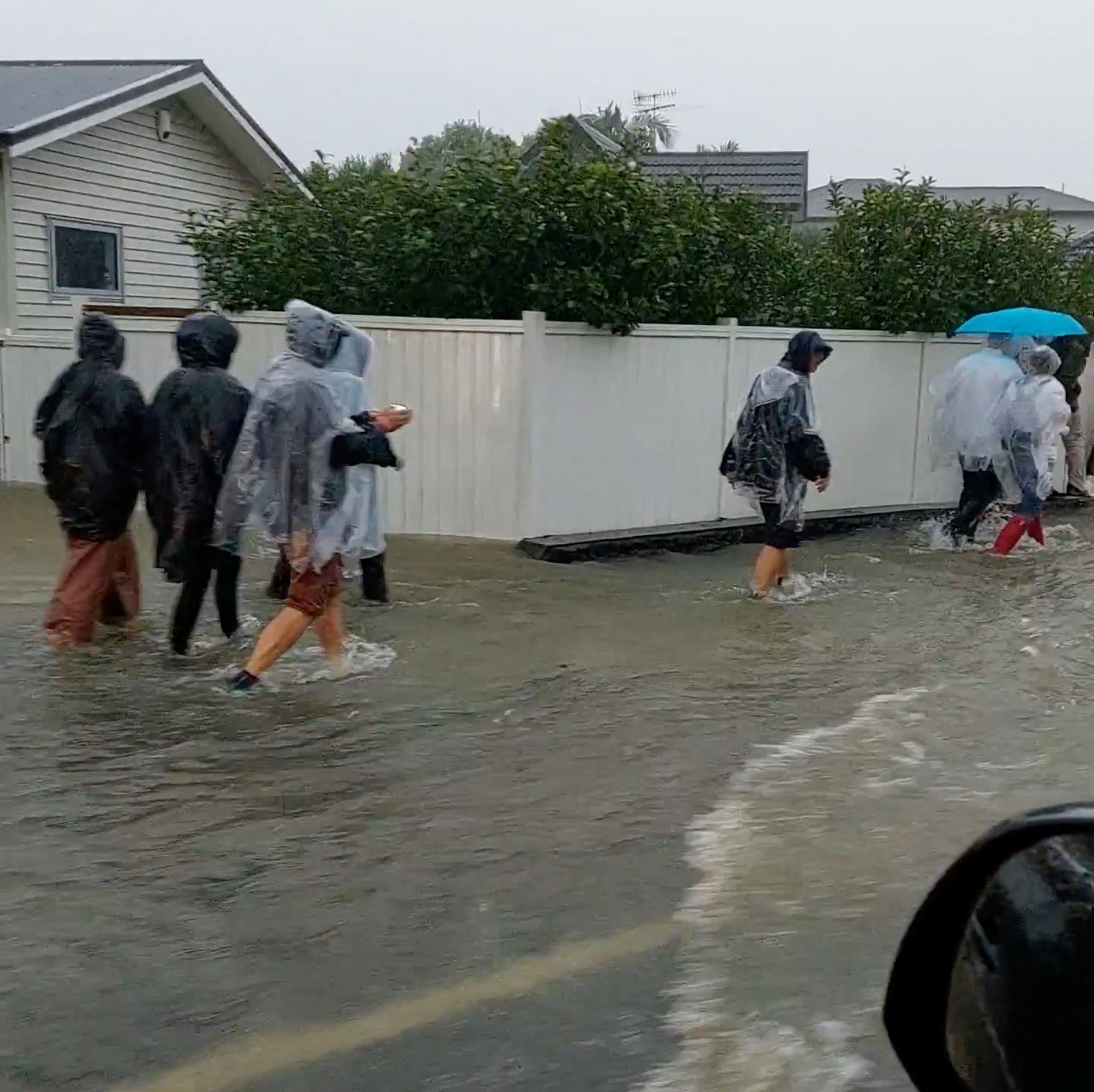 People walk on a flooded street after Elton John’s concert was canceled due to bad weather, in Auckland