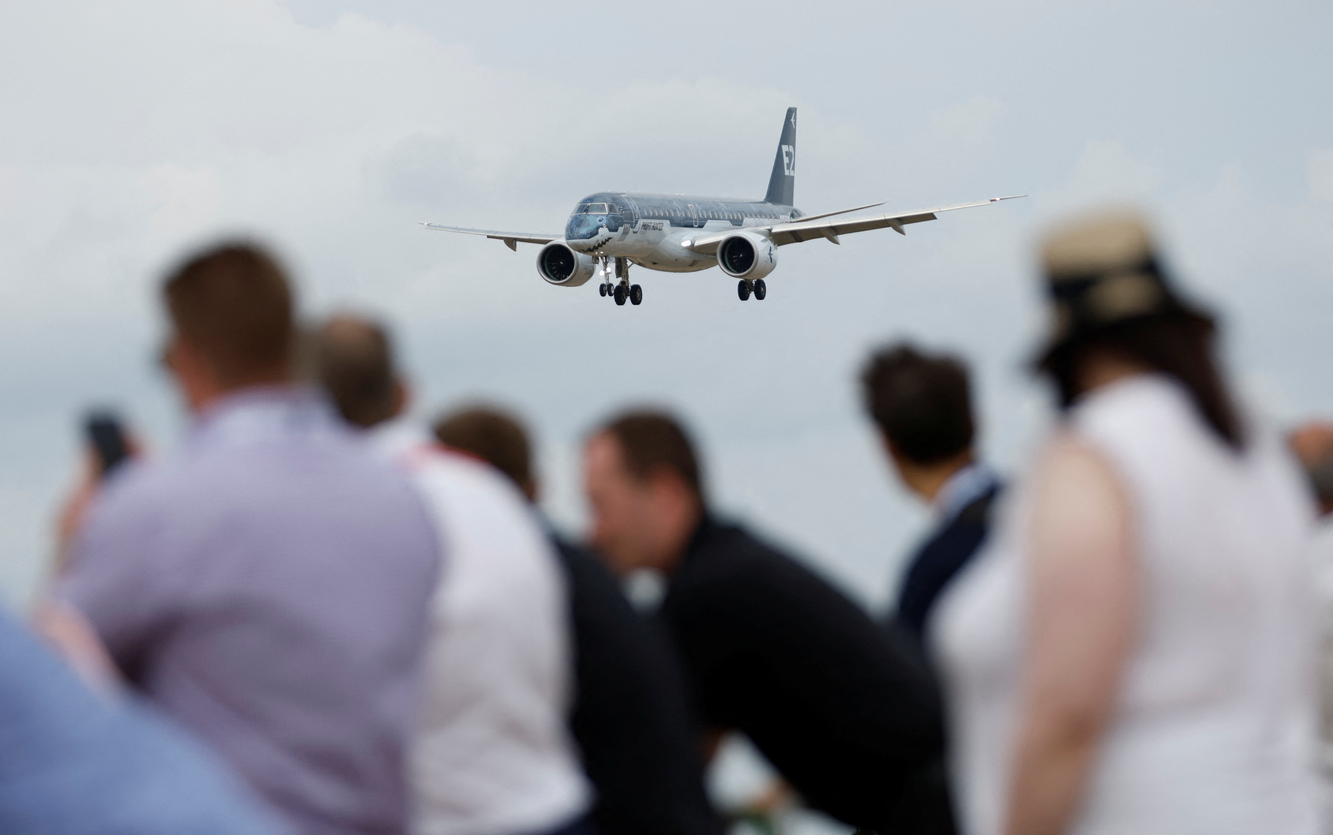 Attendees watch a Embraer 190 aircraft during a display at the Farnborough International Airshow, in Farnborough