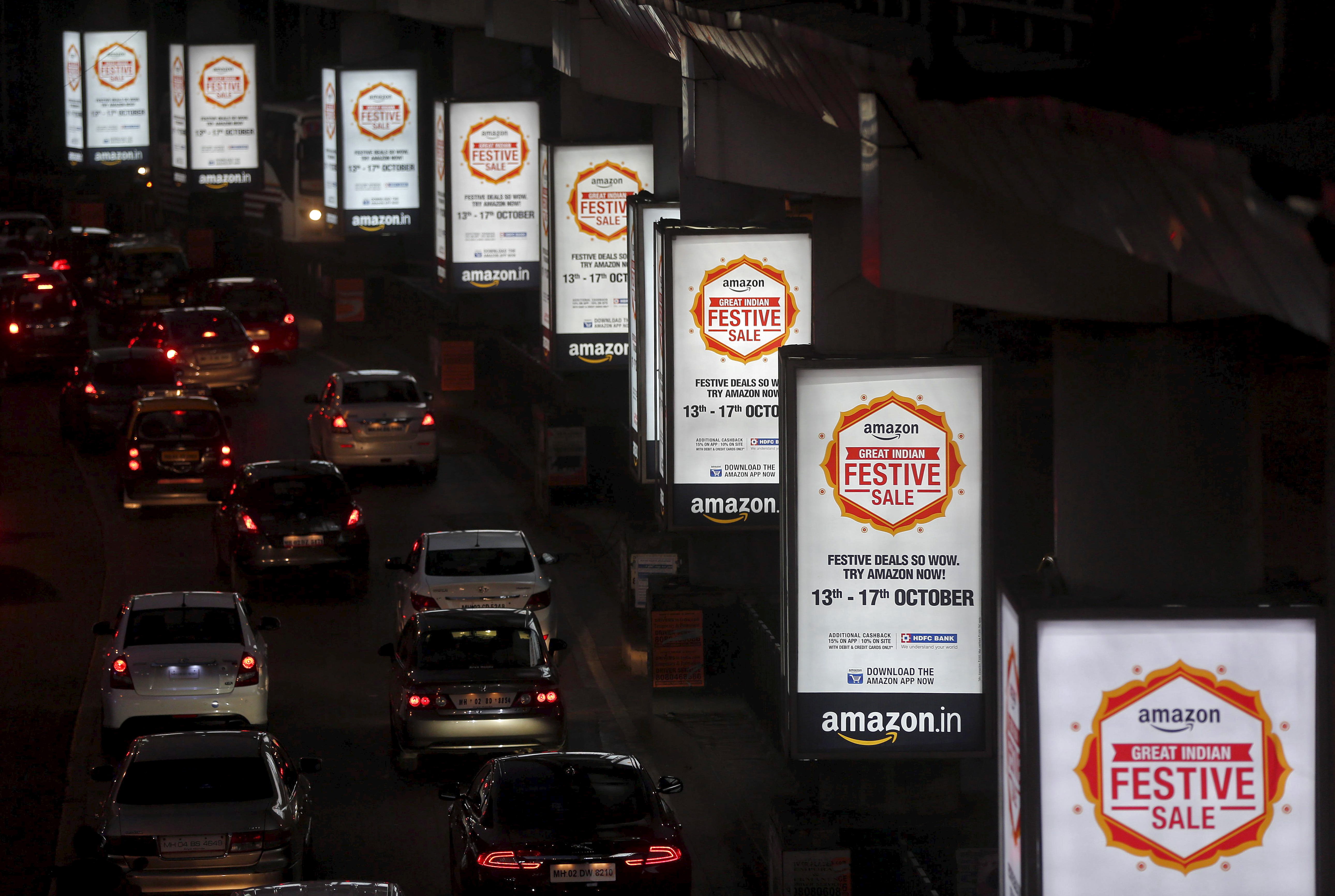 Traffic moves on a road past advertisements of Indian online marketplace Amazon, in Mumbai, India