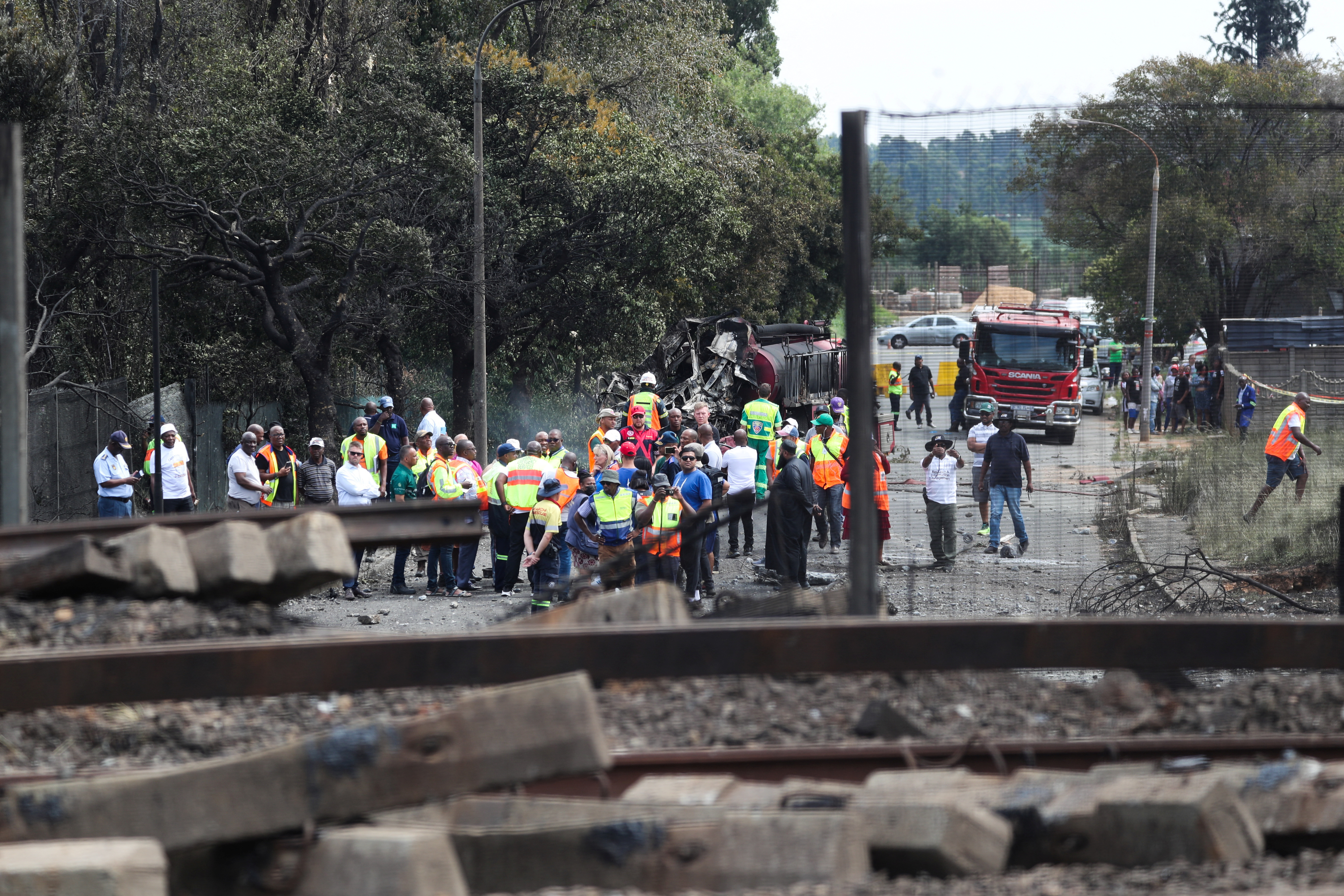 People gather near a burnt out truck at the entrance of the damaged bridge where a gas tanker exploded in Boksburg near Johannesburg