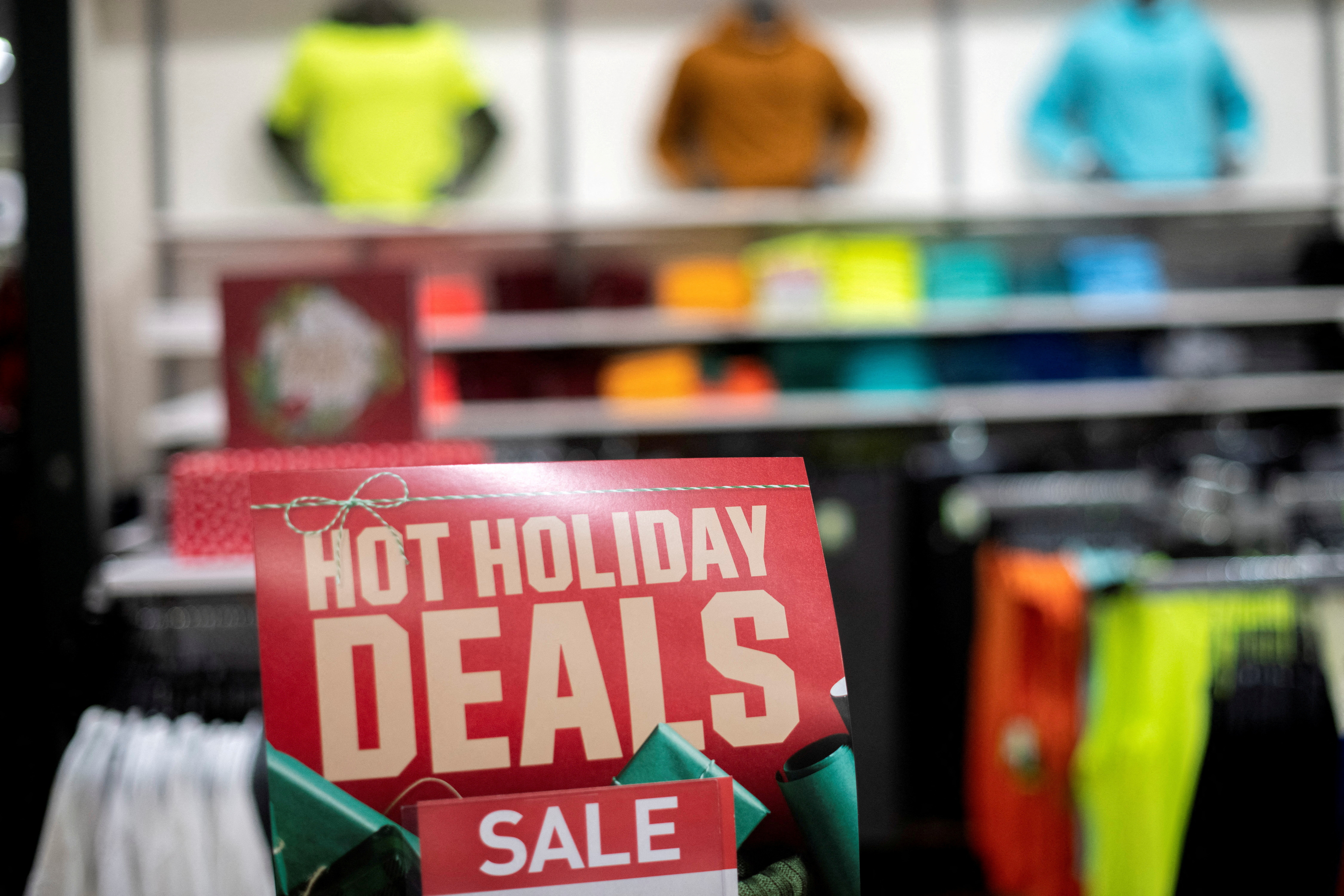 Athletic wear is displayed for sale beside a sign stating "HOT HOLIDAY DEALS SALE" at a Dick's Sporting Goods store in Collegeville