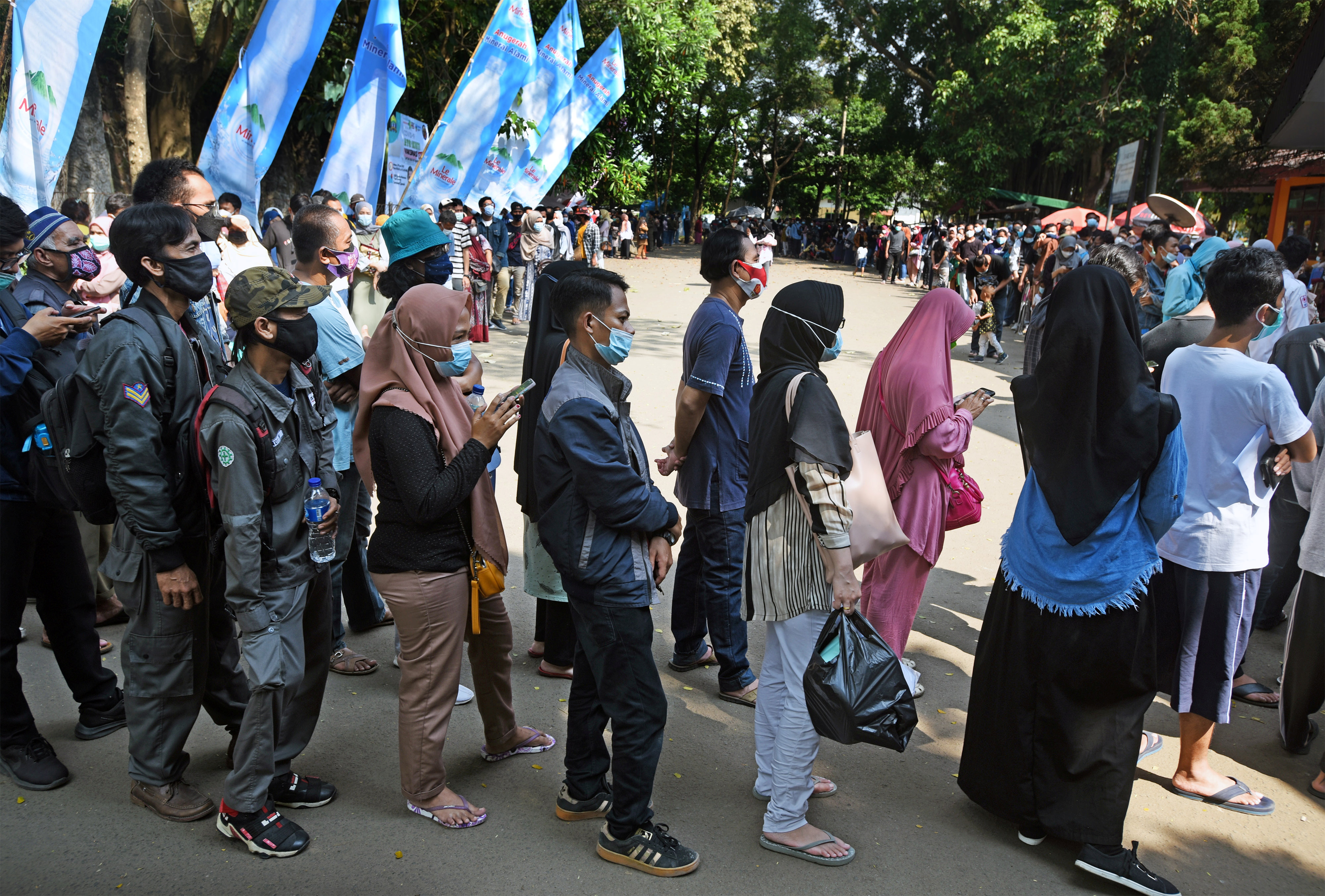 People wearing protective face masks stand in line while waiting to receive their dose of vaccine for the coronavirus disease (COVID-19) during the mass vaccination program at a sports arena