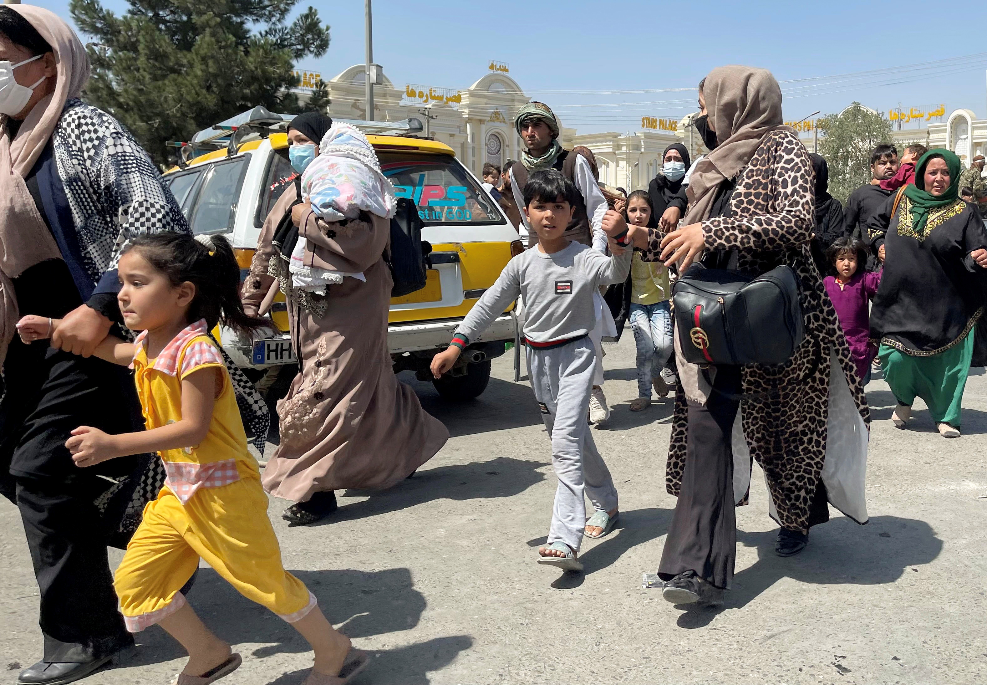 Women with their children try to get inside Hamid Karzai International Airport in Kabul, Afghanistan August 16, 2021. REUTERS/Stringer