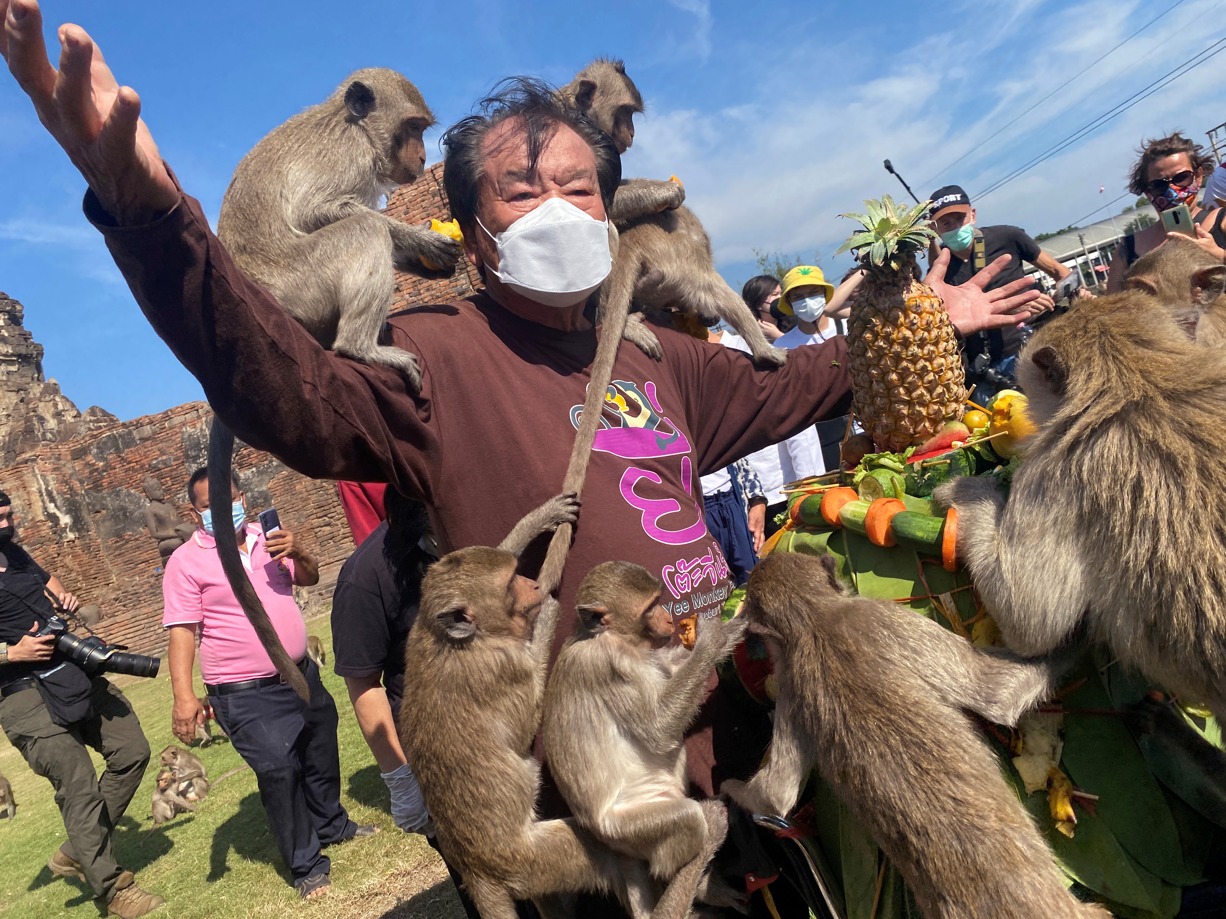 Monkeys cling onto an organiser while eating fruit during  the annual Monkey Festival, which resumed after a two-year hiatus due to the COVID-19 pandemic, in Lopburi province, Thailand, November 28, 2021. REUTERS/Jiraporn Kuhakan