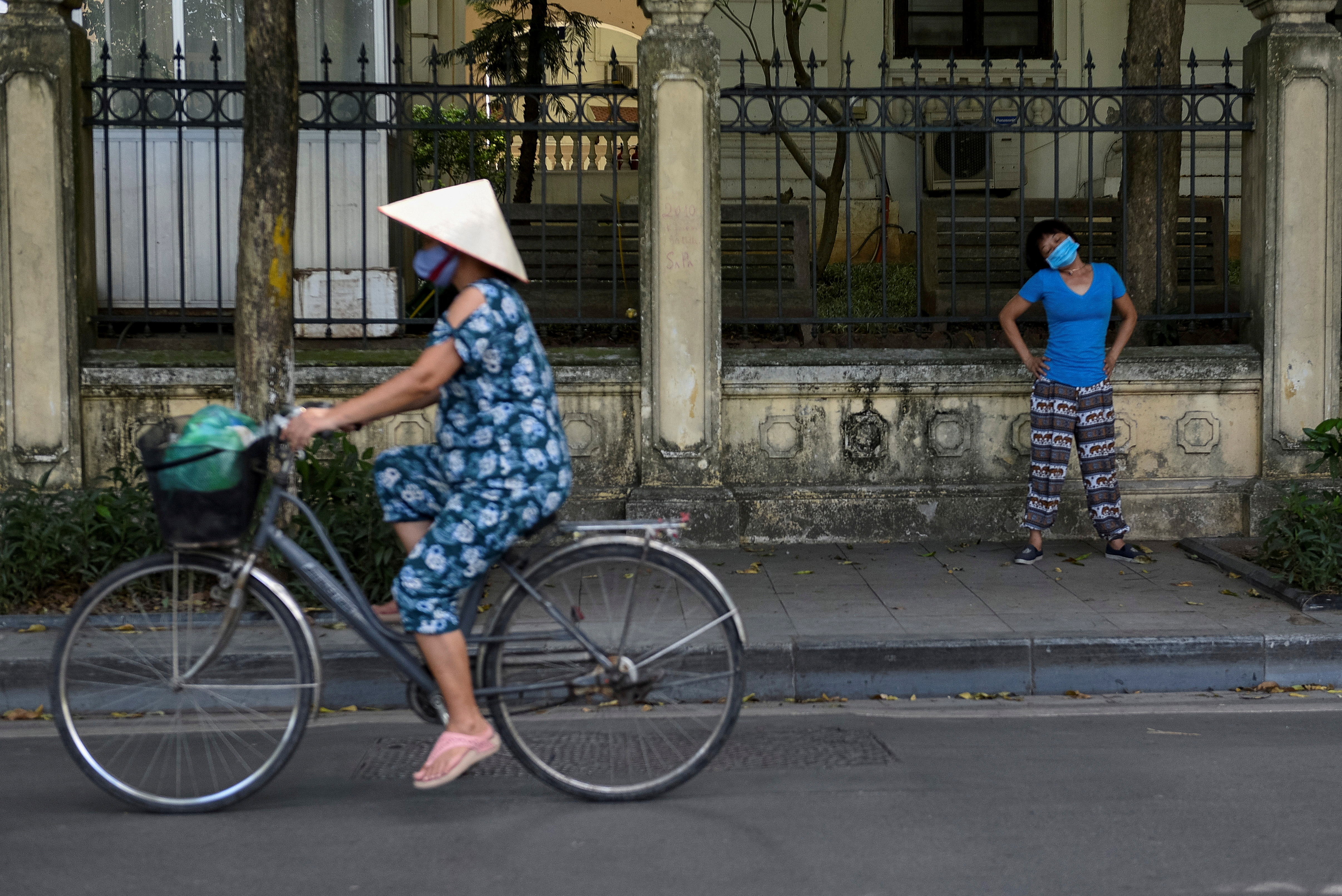 A woman wears a protective mask as she exercises on the street amid COVID-19 pandemic, in Hanoi