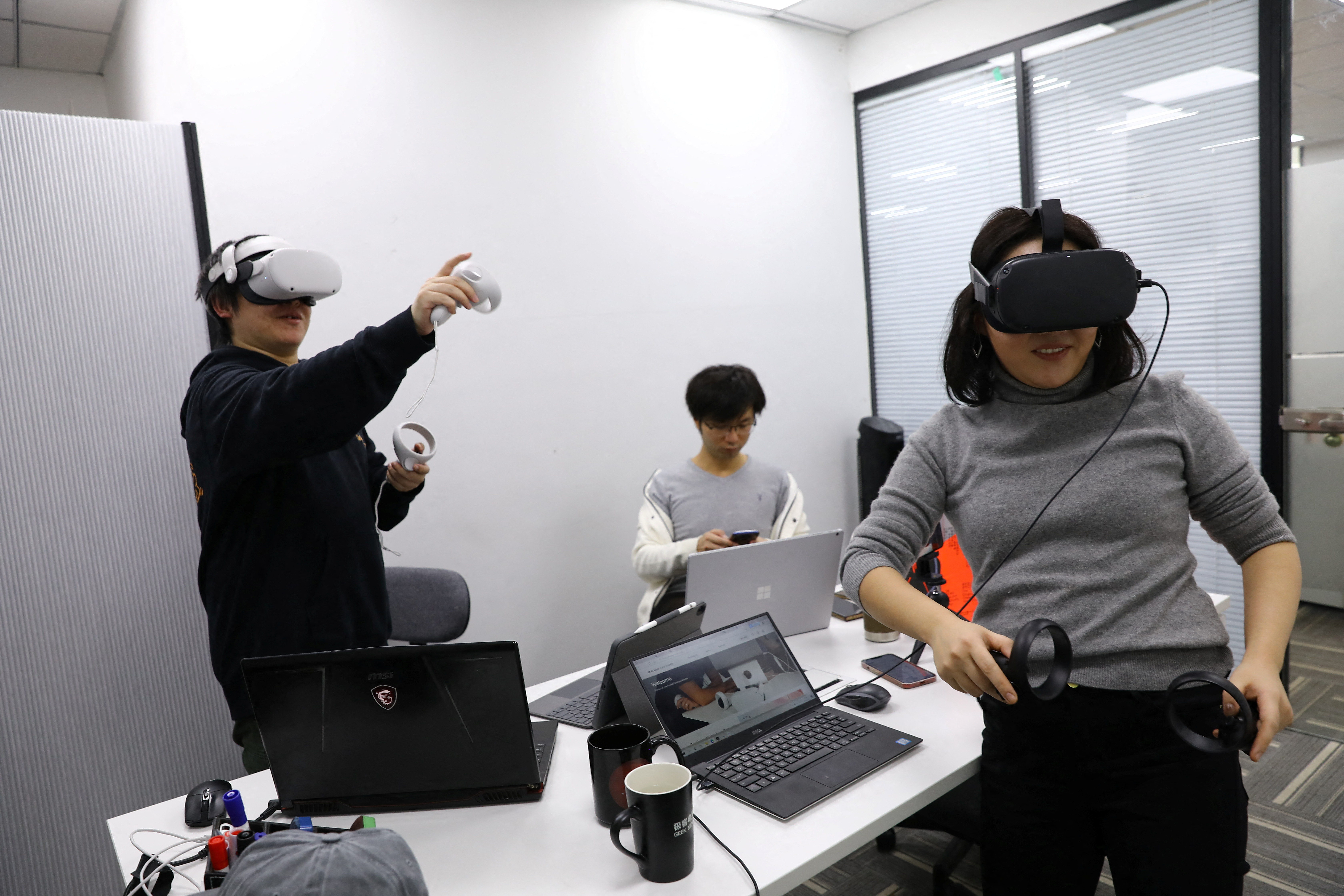 Pan Bohang, founder of vHome, a VR social gaming platform, wearing VR goggles speaks with a user during a virtual gathering, at an office in Beijing