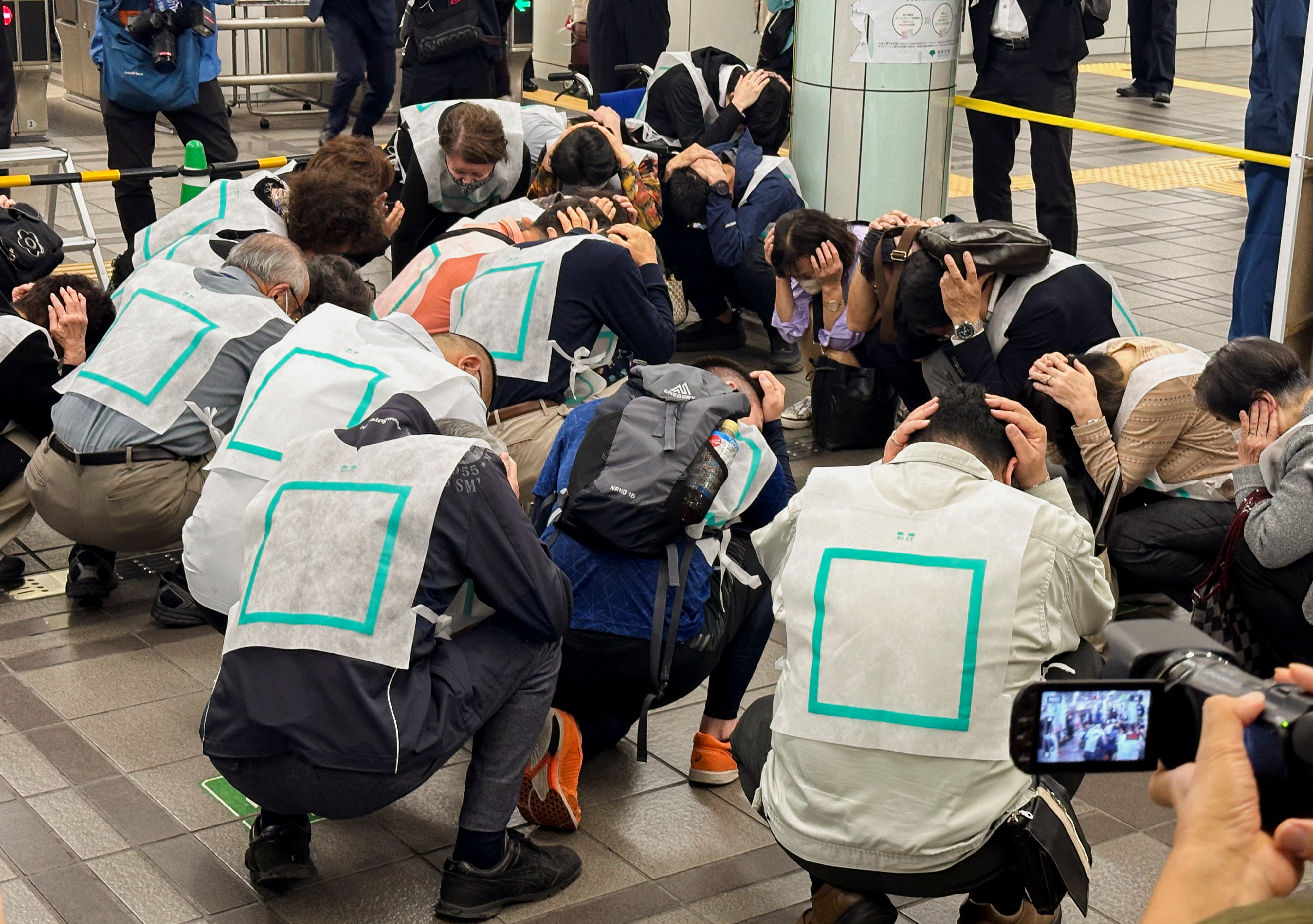 Drill participants cover their heads in a designated area inside Nerima train station in Tokyo